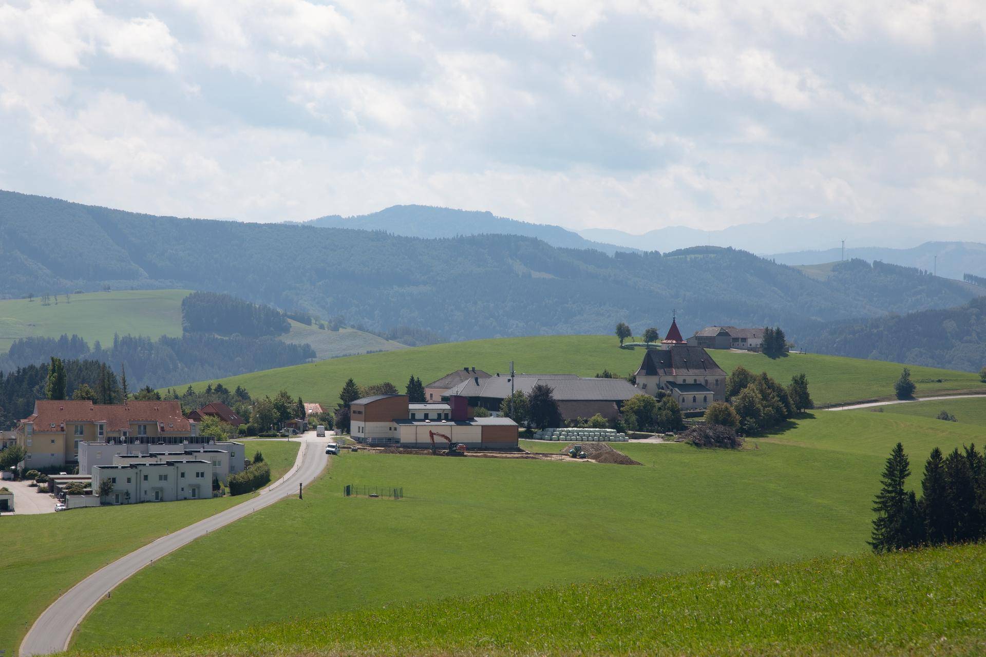 Malerische ländliche Szenerie mit grünen Hügeln, einem Dorf und einer Kirche in der Ferne.