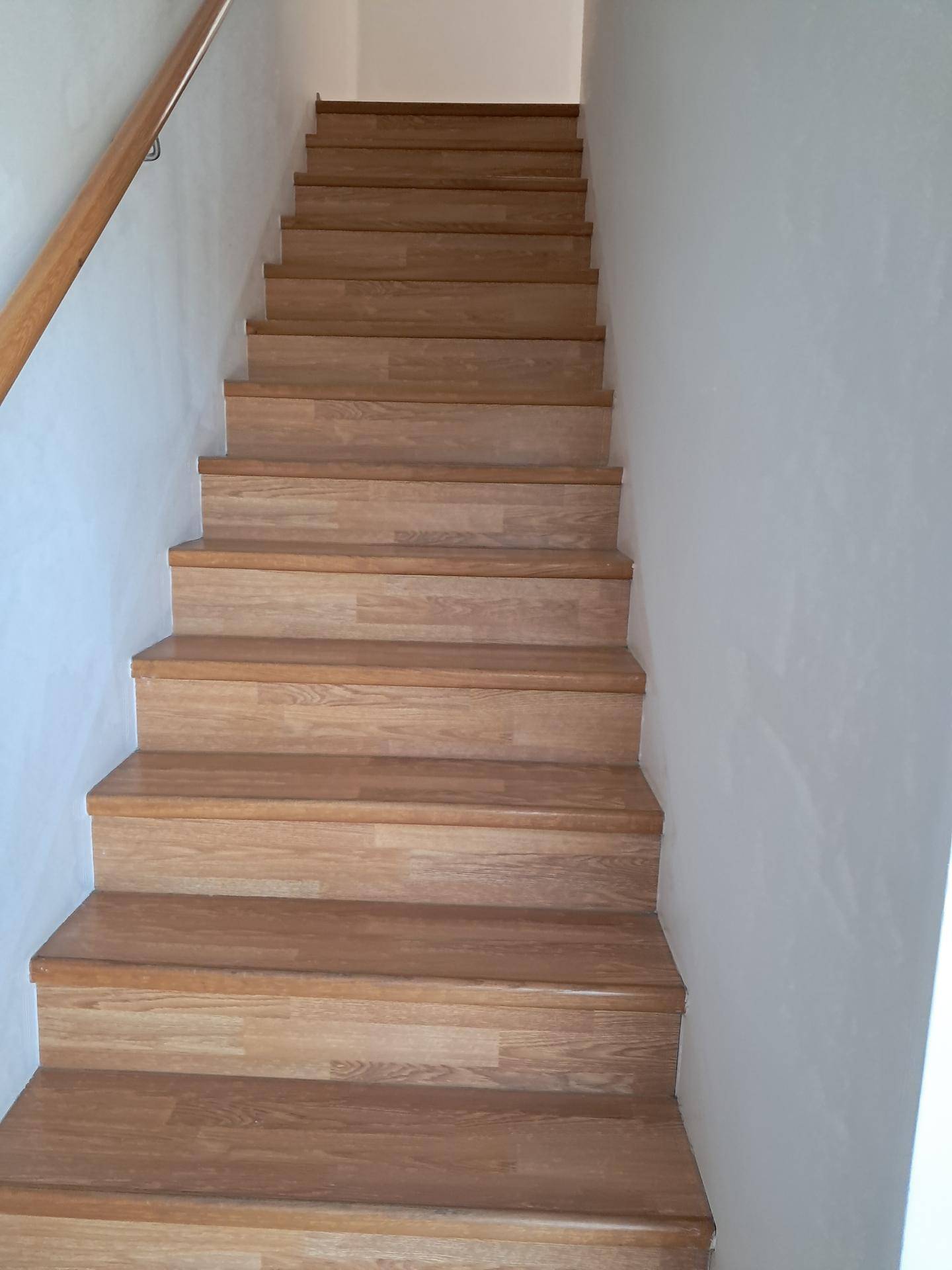 Holztreppe mit Laminatstufen, die in die obere Etage führt und einen gepflegten Eindruck macht.