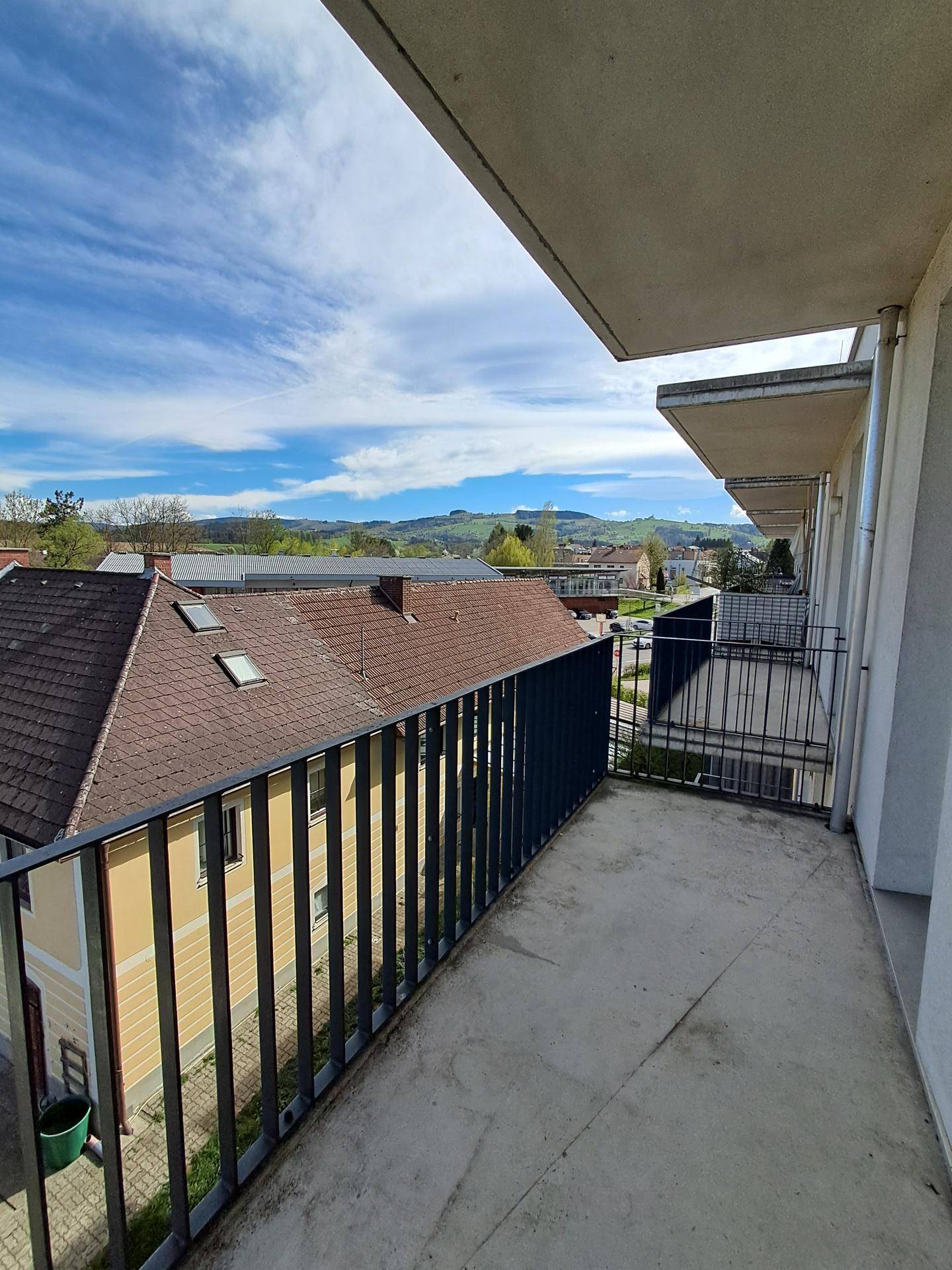 Balkon mit Metallgeländer und weitem Blick über die umliegende Landschaft und Dächer.