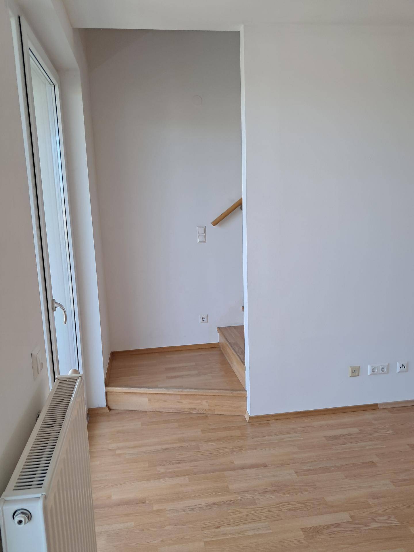 Heller Bereich mit Laminatboden und einem Treppenaufgang, der zu weiteren Räumen führt.