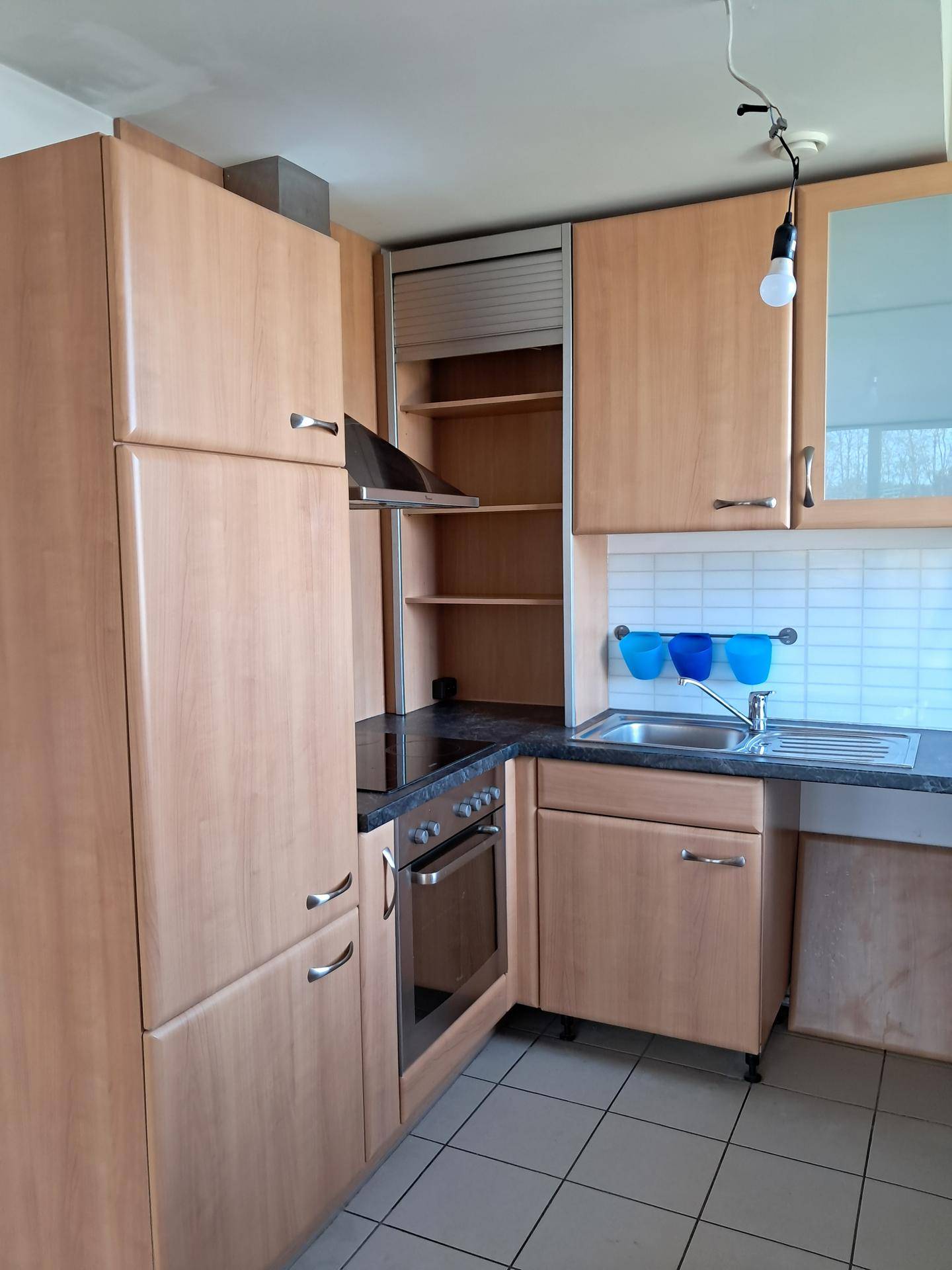 Küchenzeile mit integriertem Herd, Dunstabzugshaube und Holzschränken, die einen aufgeräumten Eindruck macht.