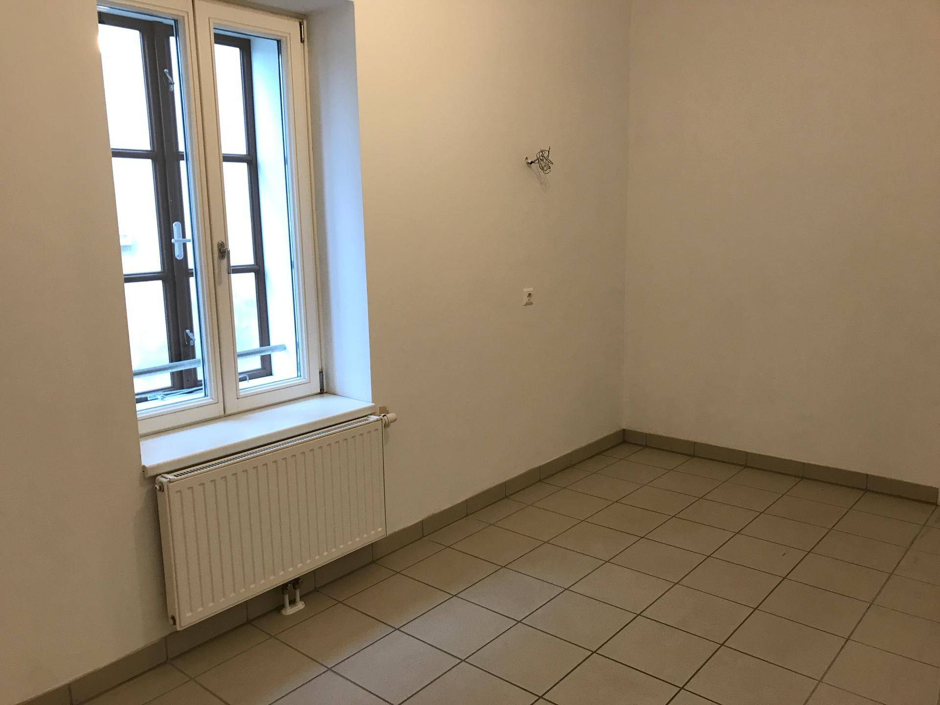 Leerer Raum, vorbereitet für eine Küche, mit Fliesenboden und einem Fenster.