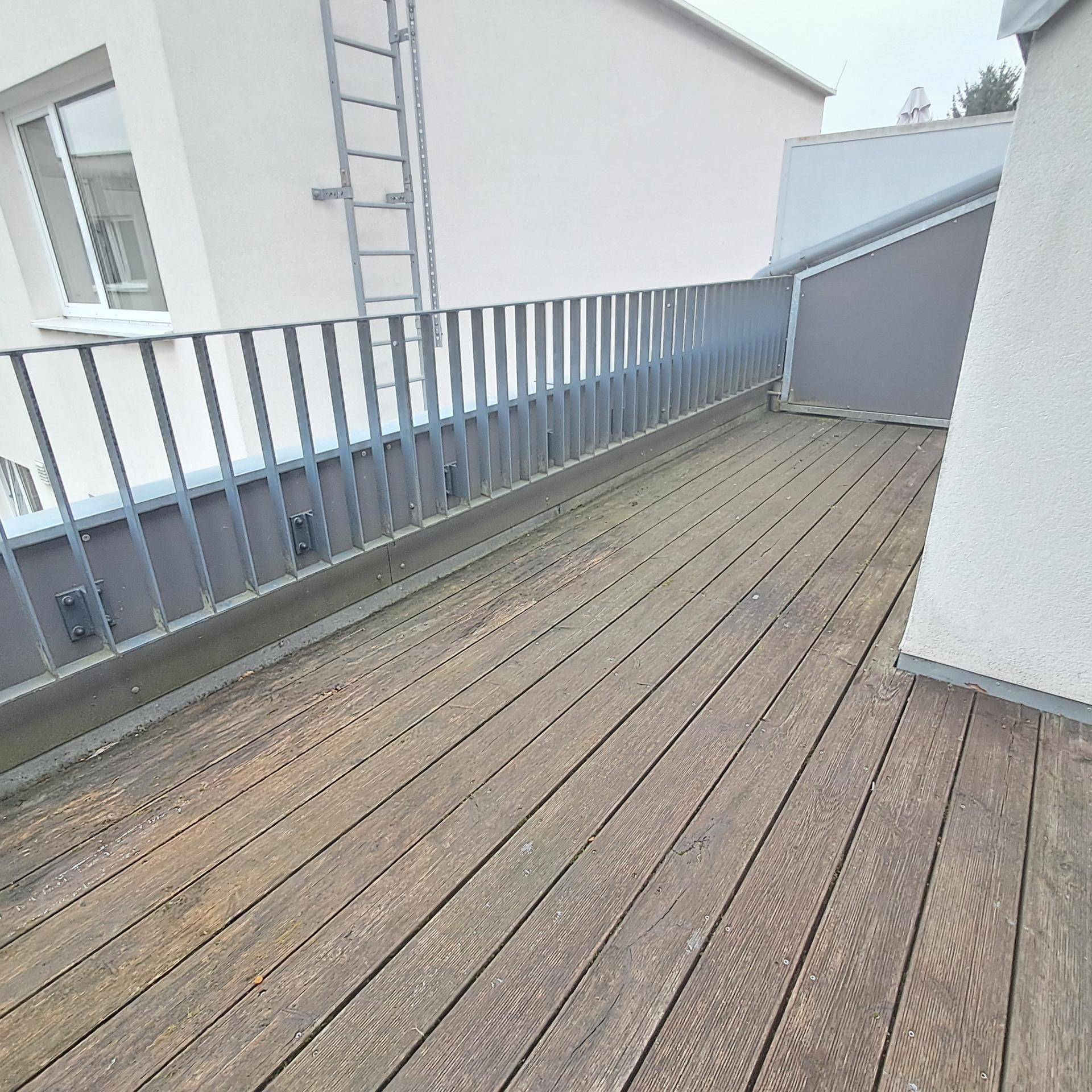 Geräumige Holzterrasse mit Metallgeländer, ideal für Entspannung im Freien.