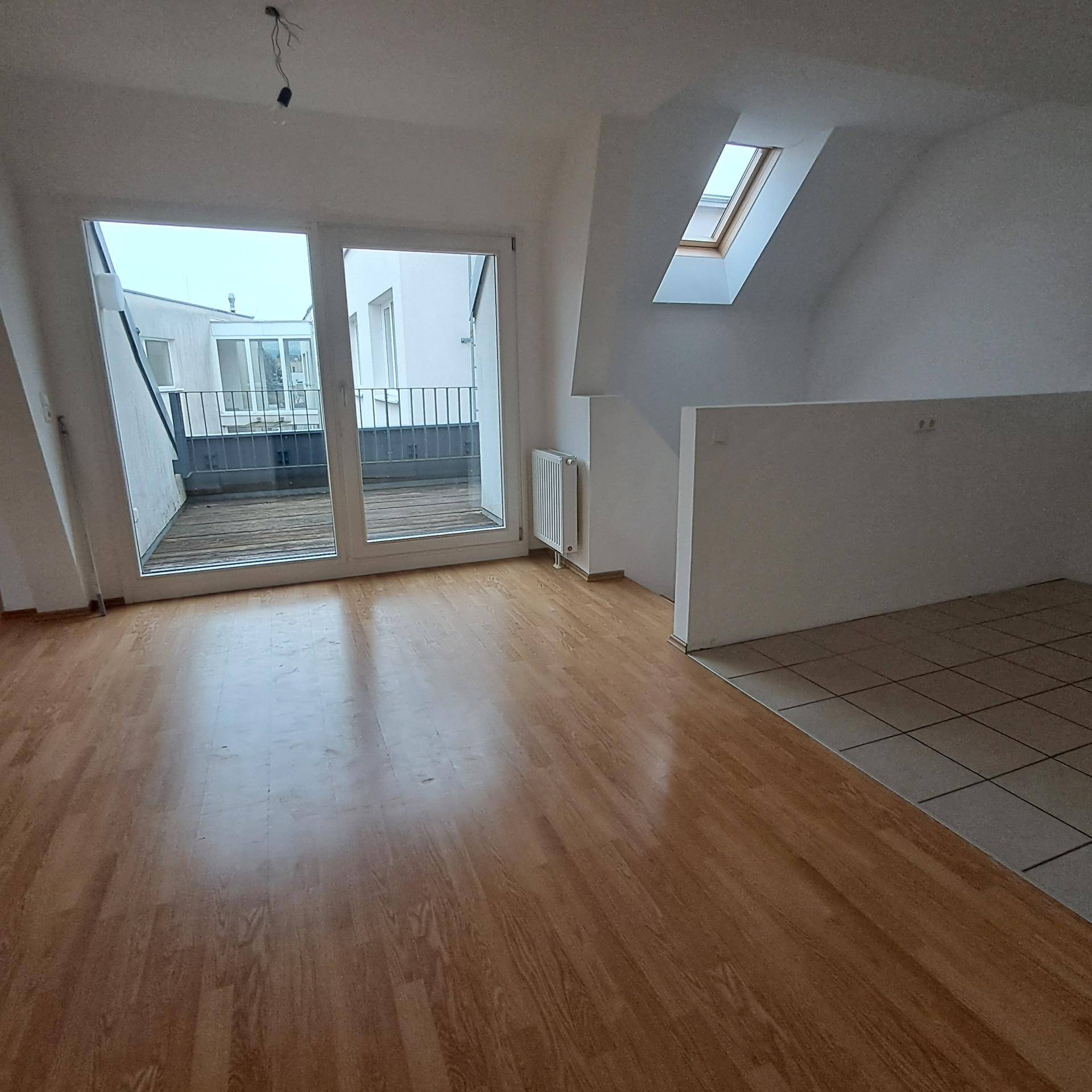 Heller Wohnbereich mit Laminatboden, Fliesenbereich und direktem Zugang zur Außenterrasse.