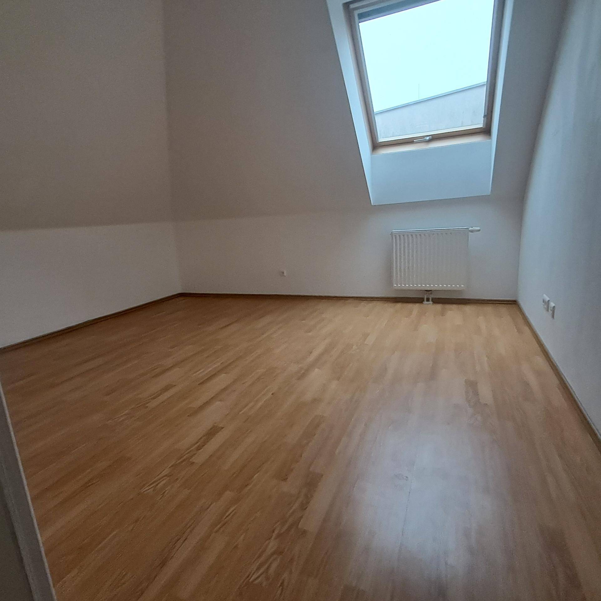 Geräumiges Schlafzimmer im Dachgeschoss mit Laminatboden, Dachfenster und viel Tageslicht.