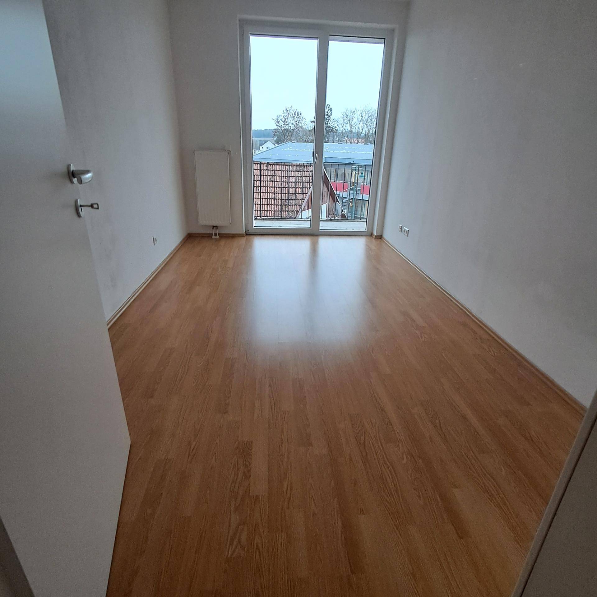 Geräumiges Schlafzimmer mit Laminatboden und Zugang zu einem Balkon, hell und einladend.
