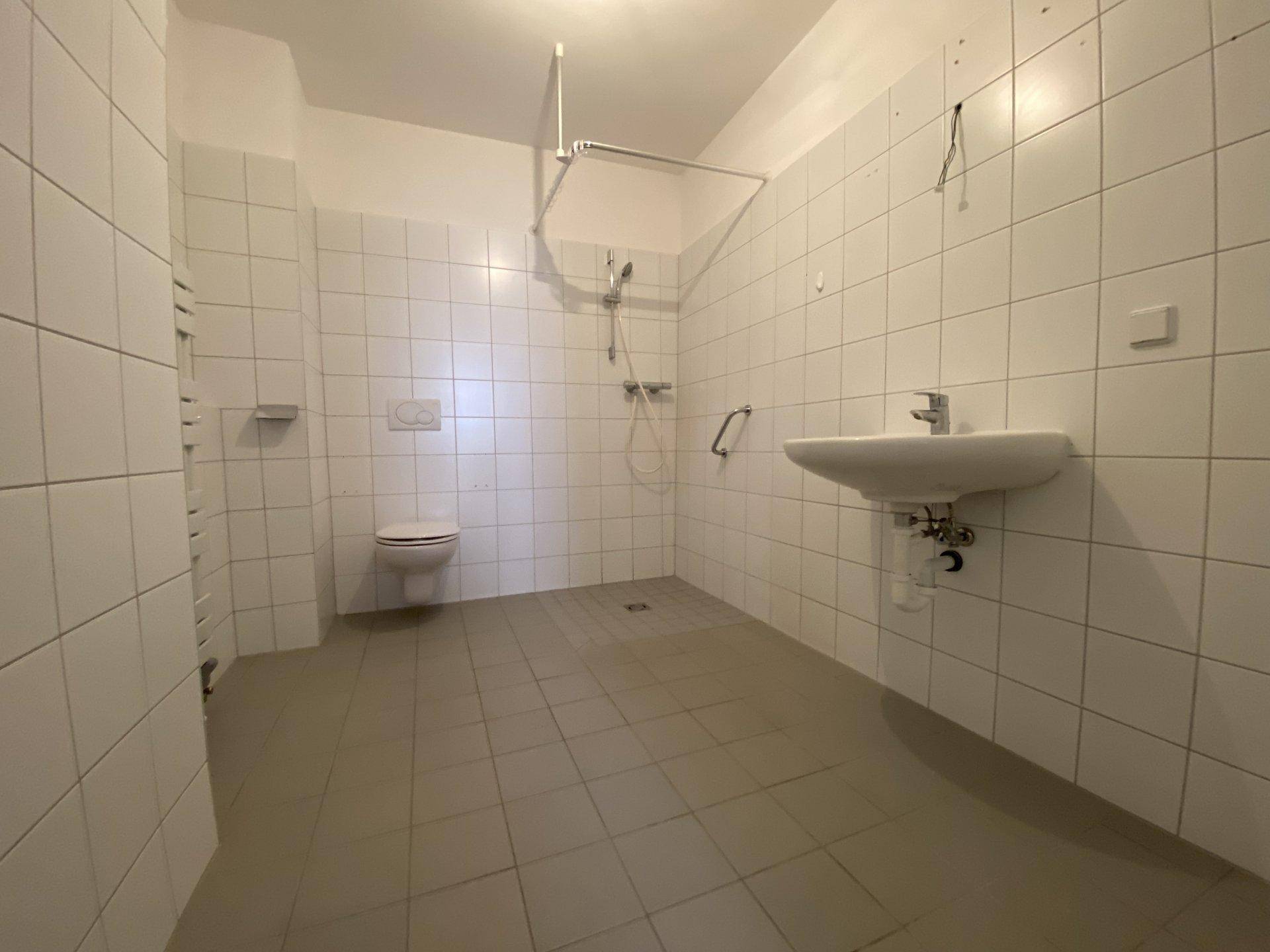 Geräumiges Badezimmer mit Fliesenboden, wandhängendem WC und Waschbecken.