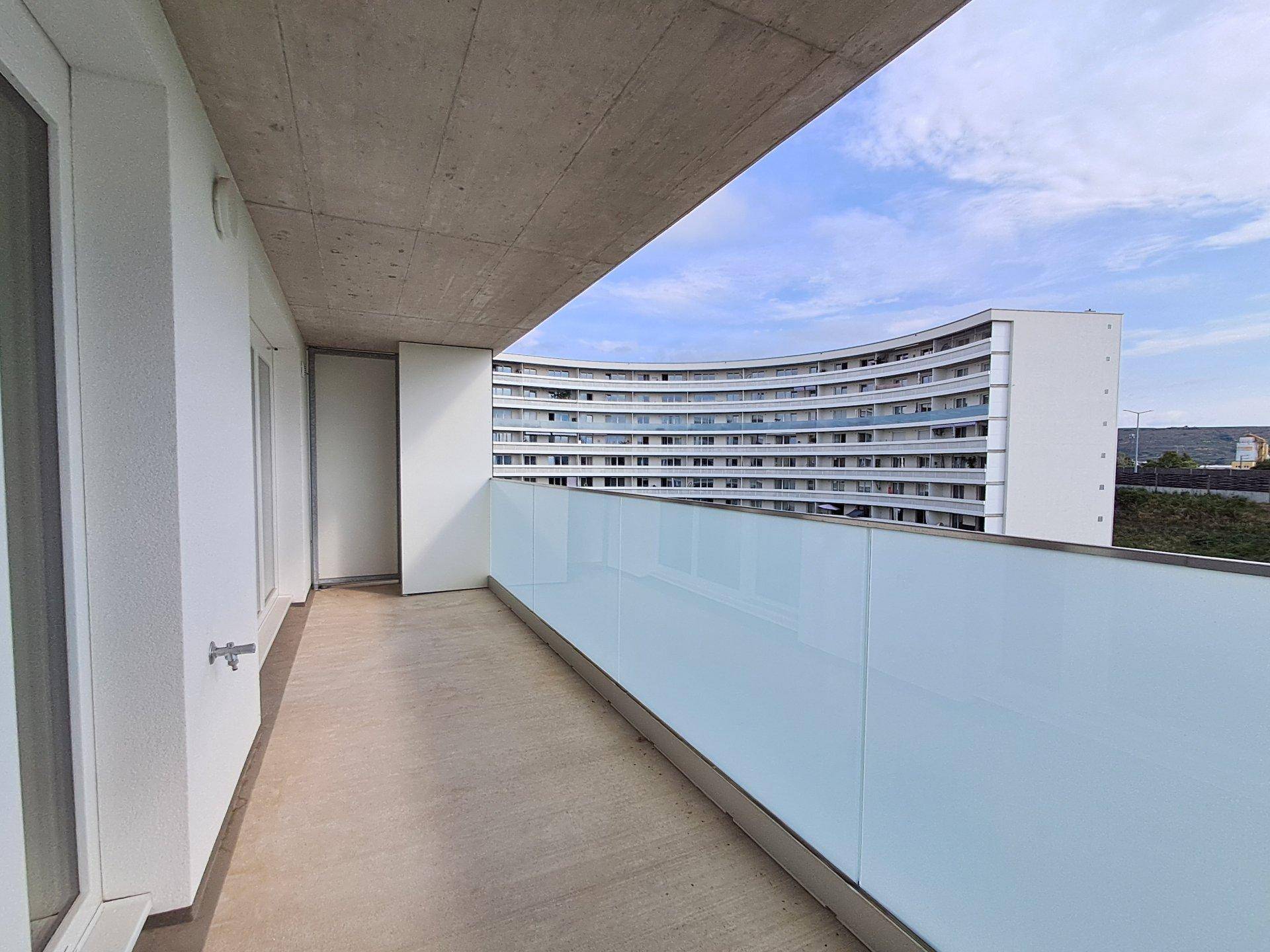 Geräumiger Balkon mit moderner Glasbrüstung und Blick auf die umliegende Bebauung.
