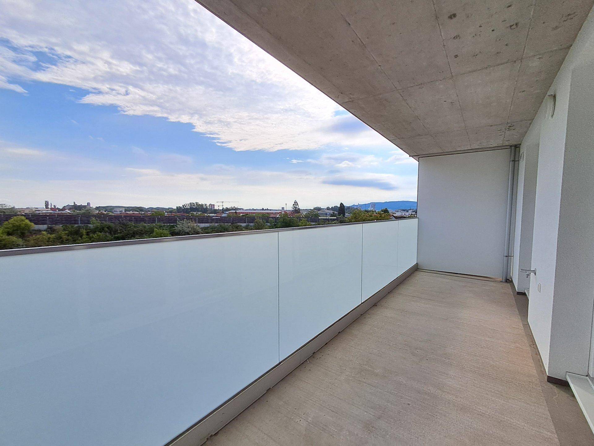 Langer Balkon mit transparenter Glasbrüstung und weitem Blick über die Stadtlandschaft.