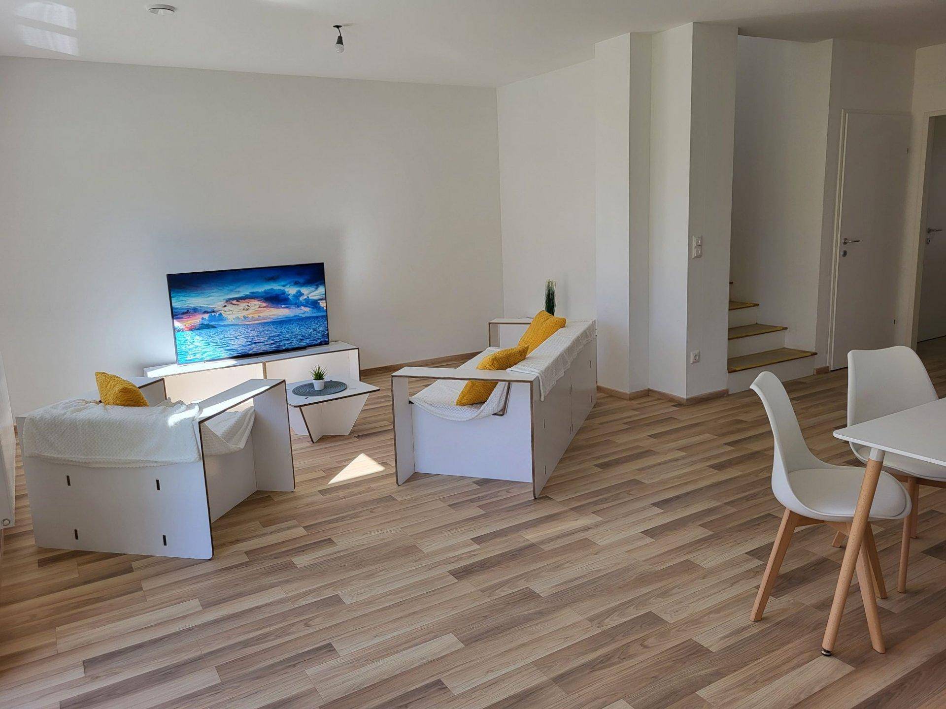 Geräumiger Wohnbereich mit Fernseher und Zugang zu den oberen Etagen.