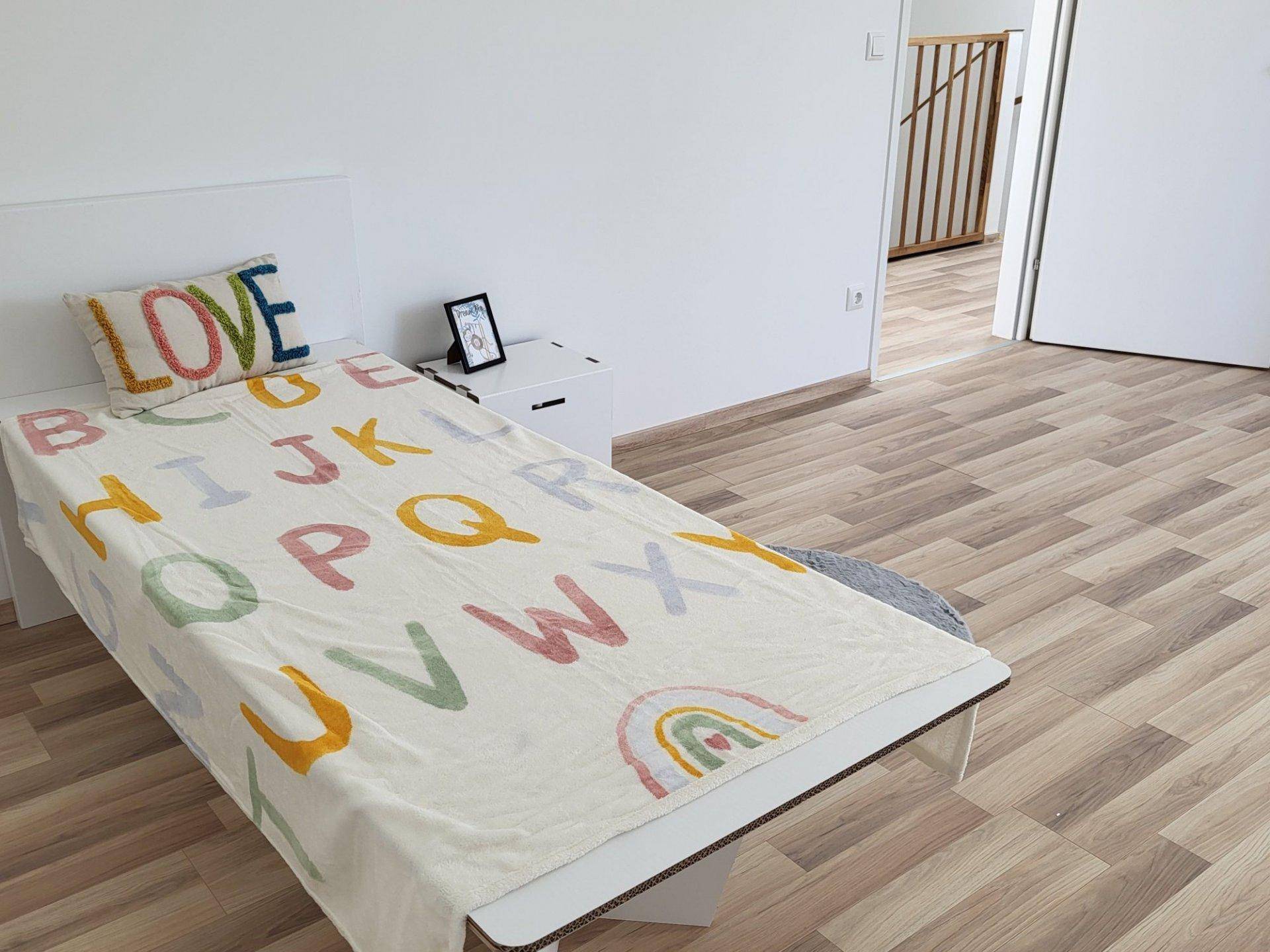 Helles Kinderzimmer mit Laminatboden und bunter Bettwäsche, ideal für kleine Bewohner.