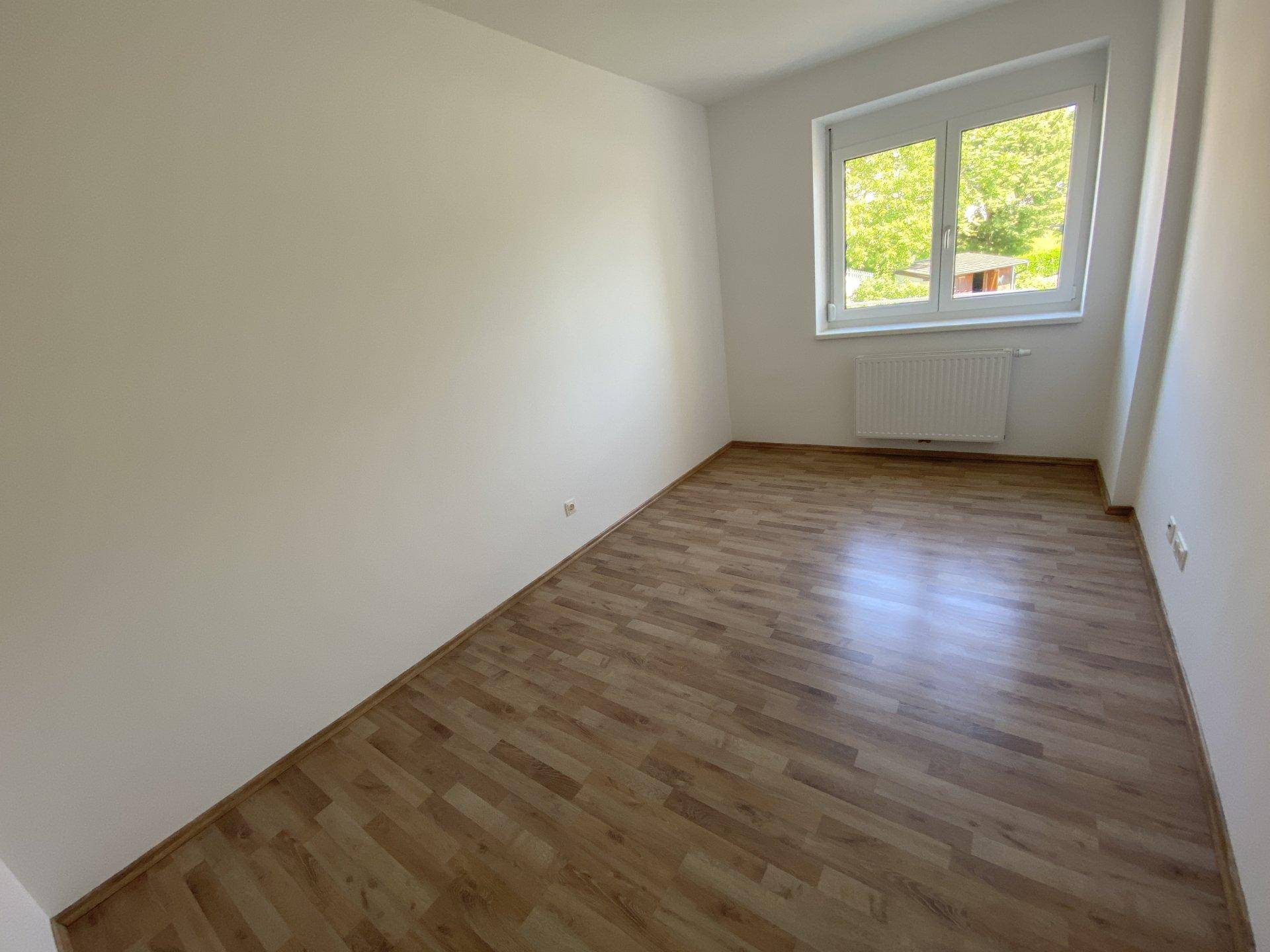 Kleines, helles Zimmer mit Laminatboden und einem Fenster, vielseitig nutzbar als Kinder- oder Arbeitszimmer.
