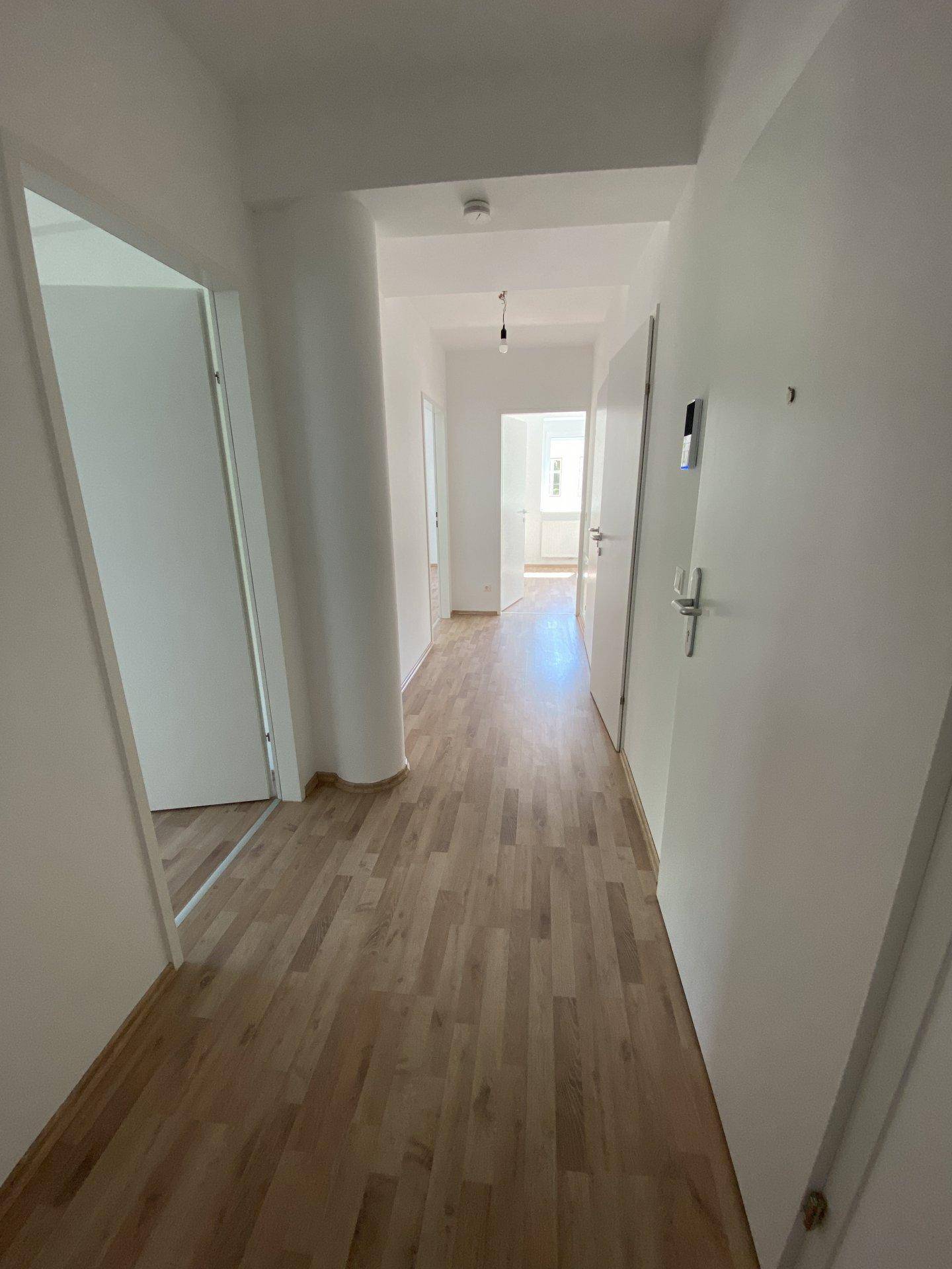 Heller Flur mit Laminatboden, der zu den verschiedenen Räumen der Wohnung führt.