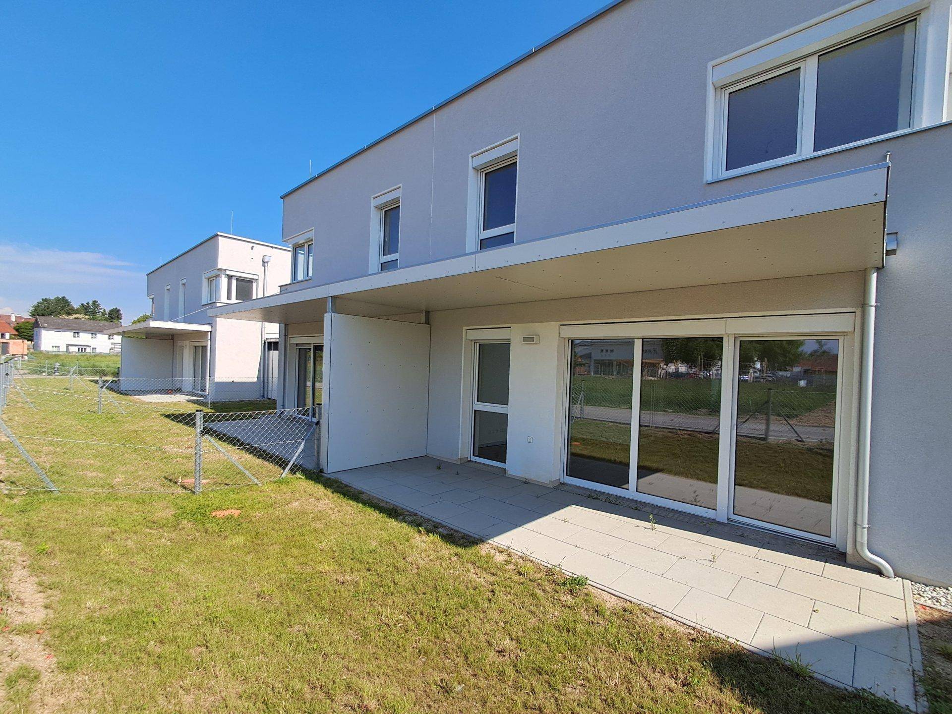 Reihenhäuser mit großzügigen Terrassen und angrenzenden Rasenflächen, ideal für Entspannung im Freien.