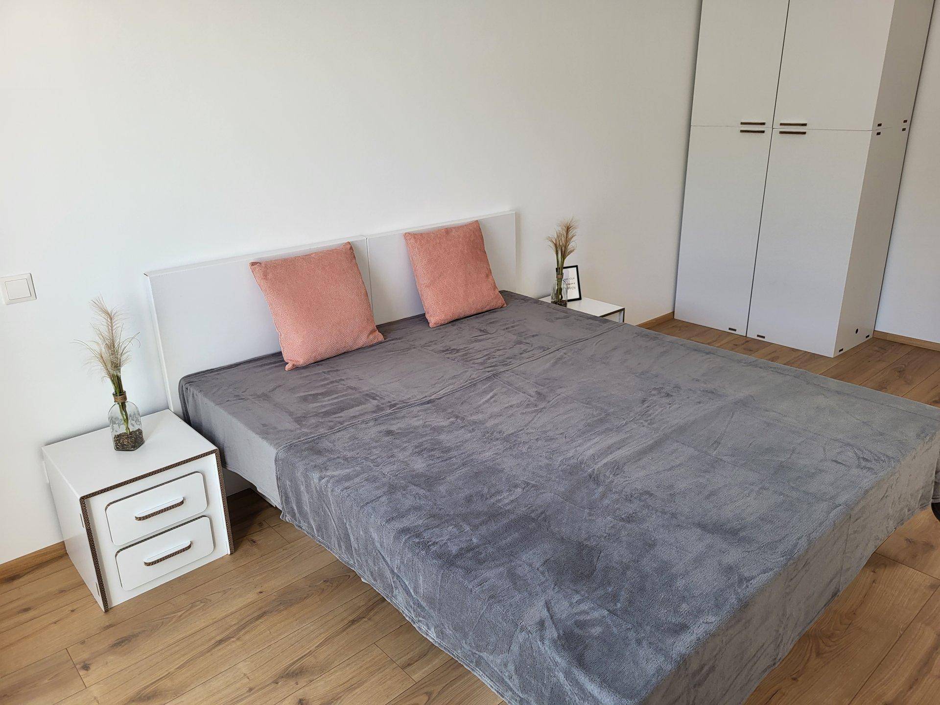 Schlafzimmer mit Doppelbett, Nachttischen und weißem Kleiderschrank auf Holzboden.