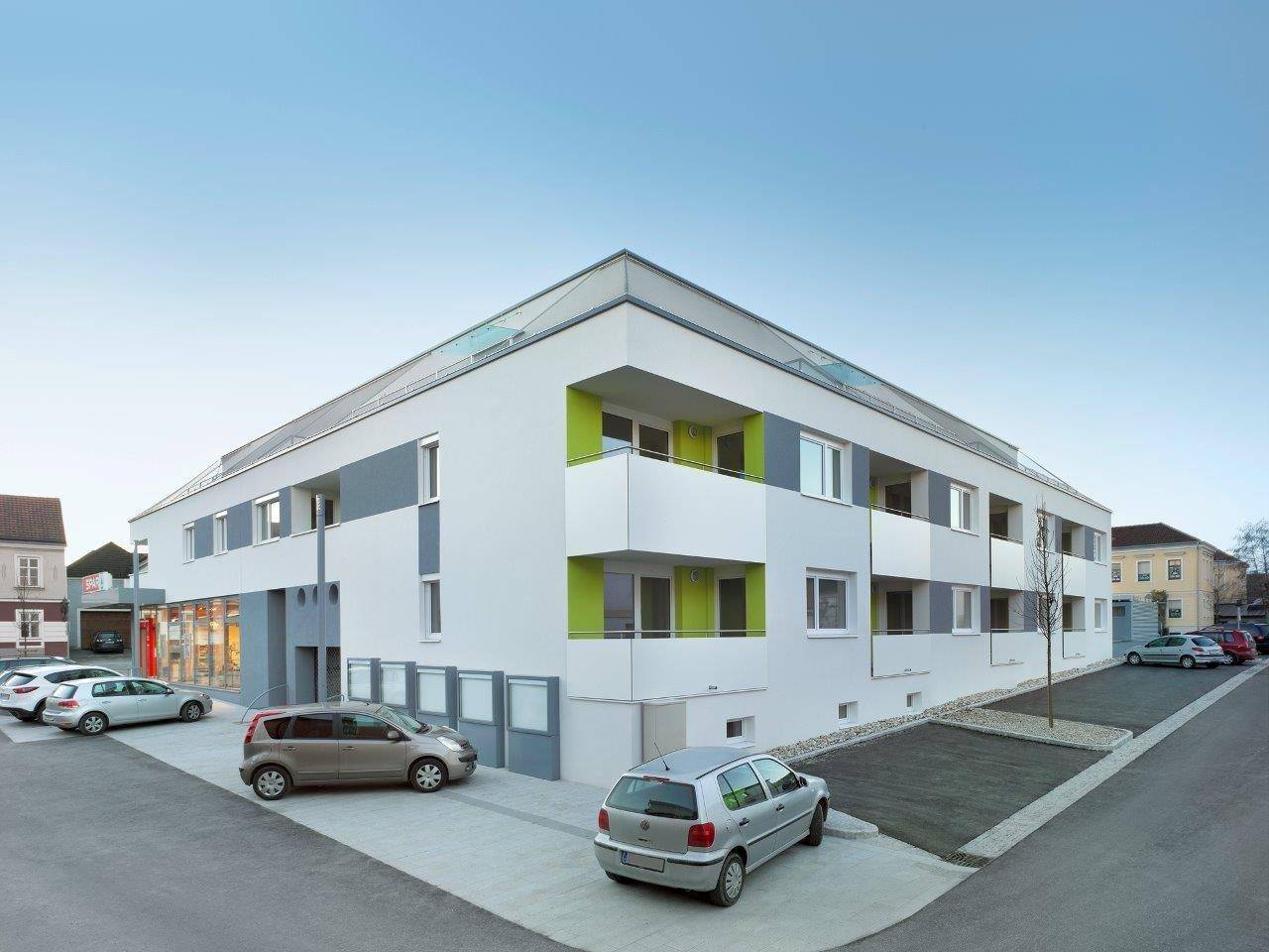 Ansicht des modernen Wohngebäudes mit Parkplätzen und Balkonen unter klarem Himmel.