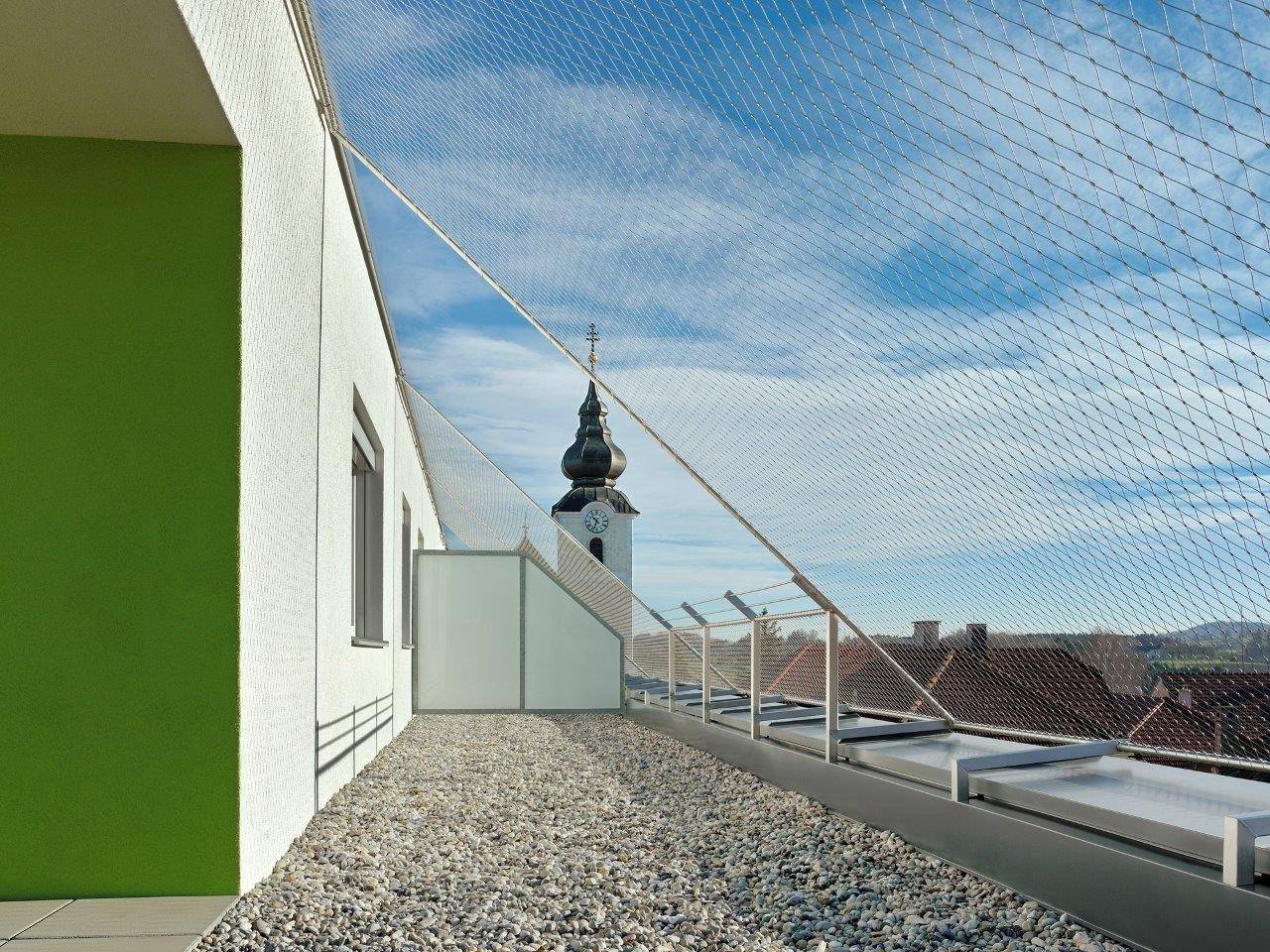Dachterrasse mit Kiesbelag und weitem Blick auf die Umgebung und Kirchturm.
