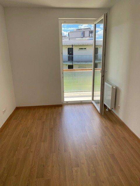 Helles Schlafzimmer mit Parkettboden und direktem Zugang zu einem Balkon.