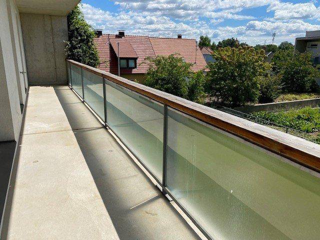 Geräumiger Balkon mit moderner Glasbrüstung und Holzakzenten, ideal für Entspannung.