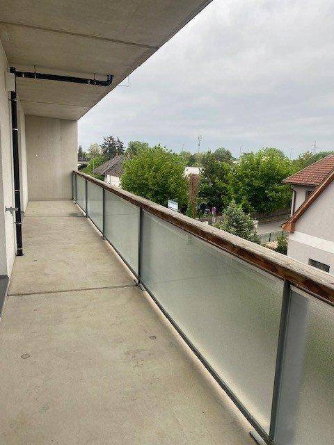 Geräumiger Balkon mit Glasgeländer und Blick auf die grüne Umgebung.