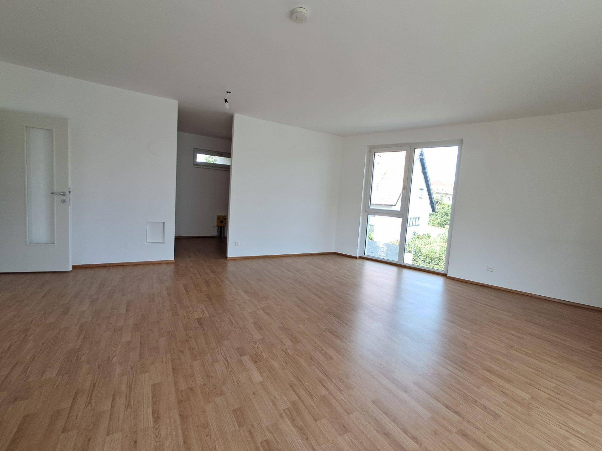 Geräumiges Wohnzimmer mit Laminatboden und weiß gestrichenen Wänden.