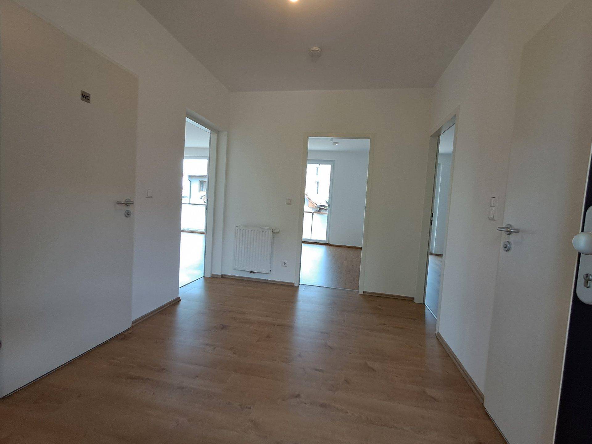 Heller Flur mit Laminatboden und Zugang zu mehreren Zimmern.