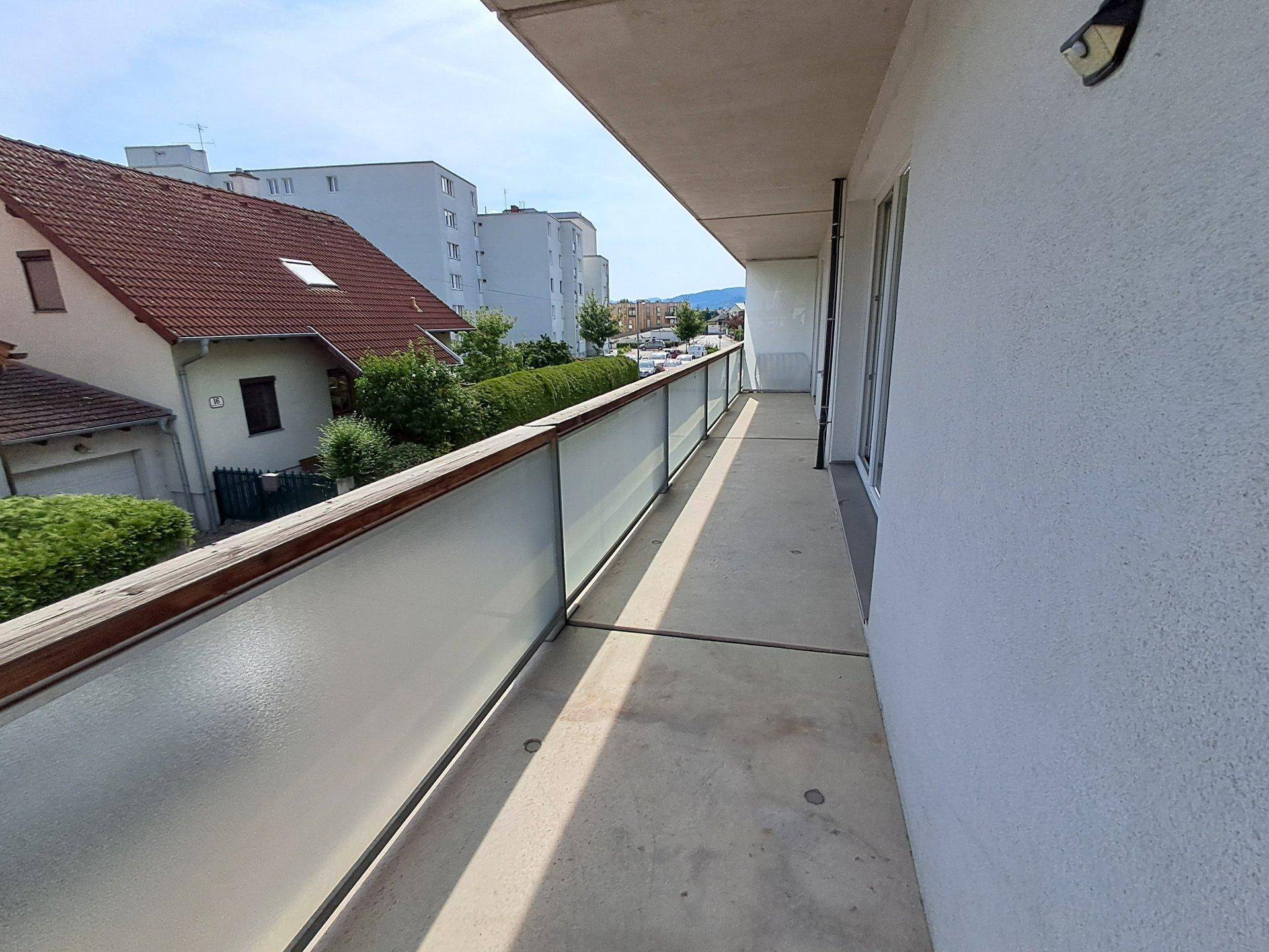 Langer Balkon mit Milchglasgeländer und weitem Blick auf die Umgebung.
