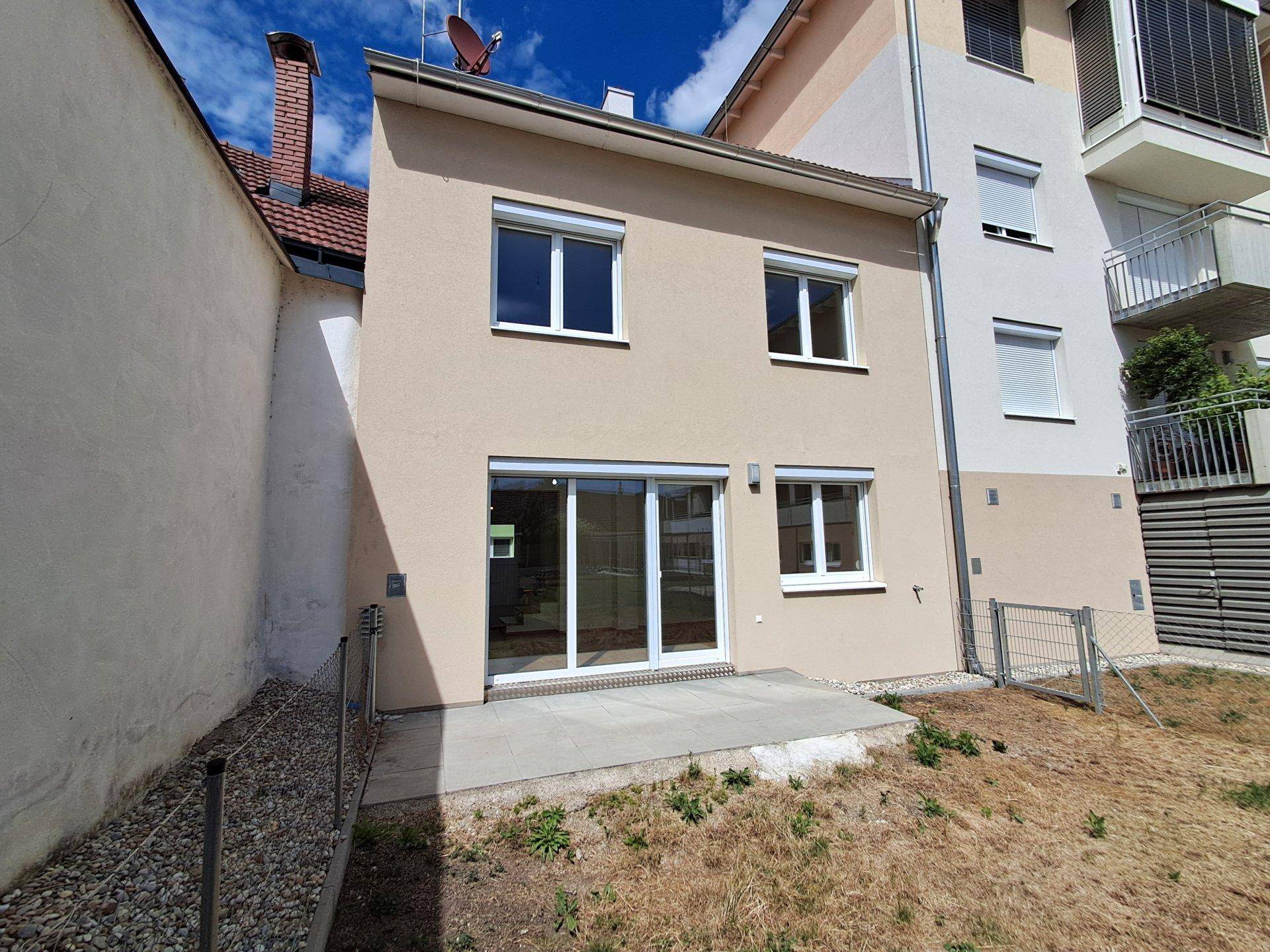 Kleine Terrasse mit Zugang zum Haus und Blick auf den Gartenbereich.