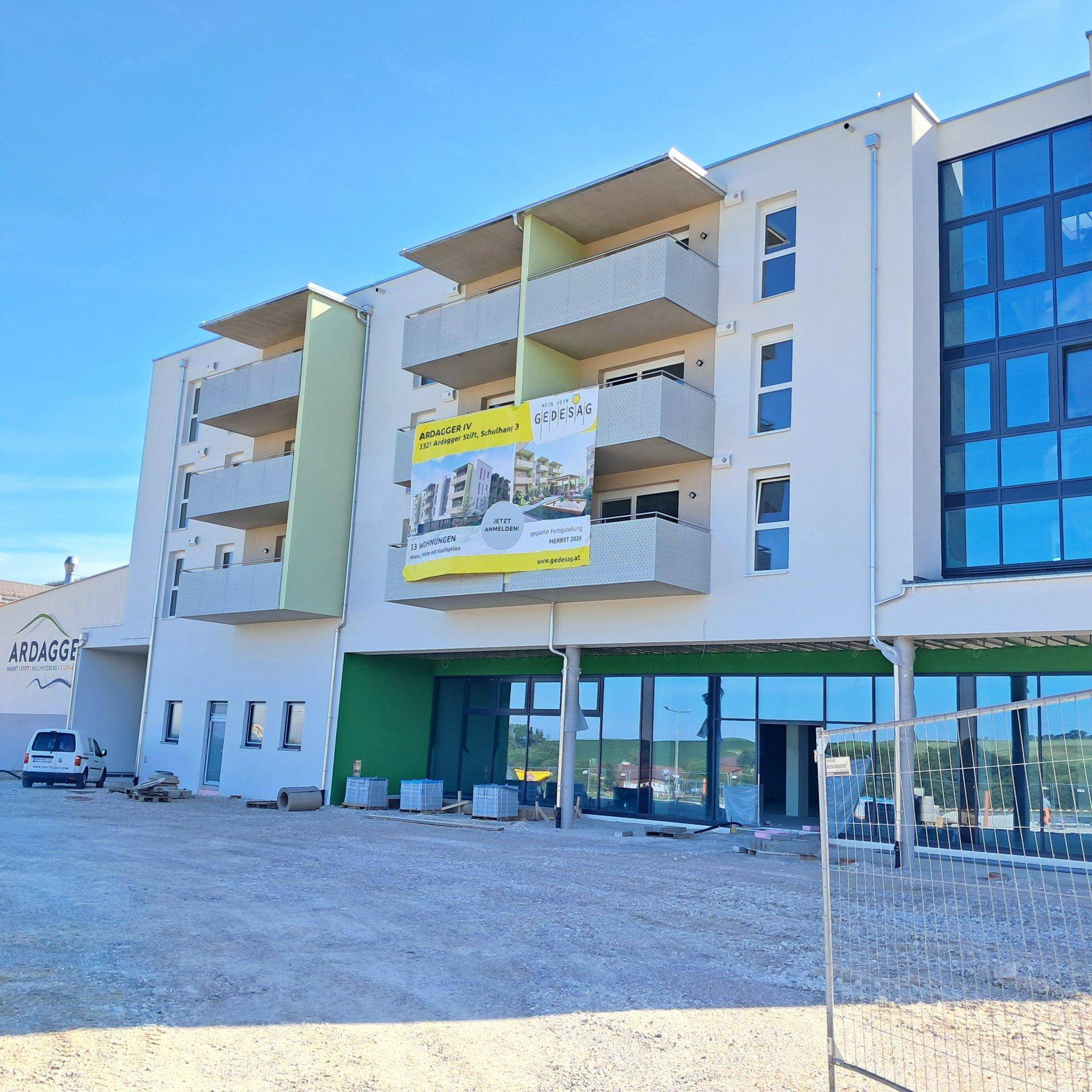 Neubau-Wohngebäude mit moderner Architektur, Balkonen und einem Werbebanner an der Fassade.
