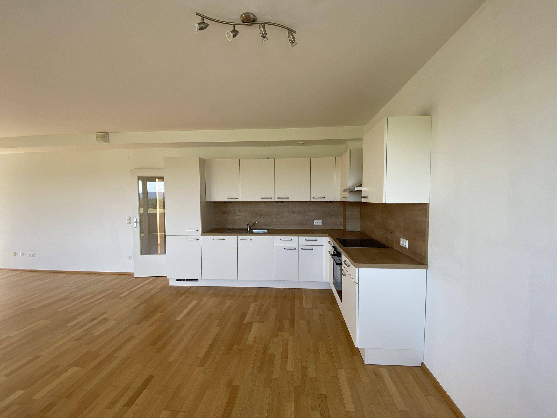 Funktionale Küche mit weißen Fronten und Holzdetails, offen zum Wohnbereich gestaltet.