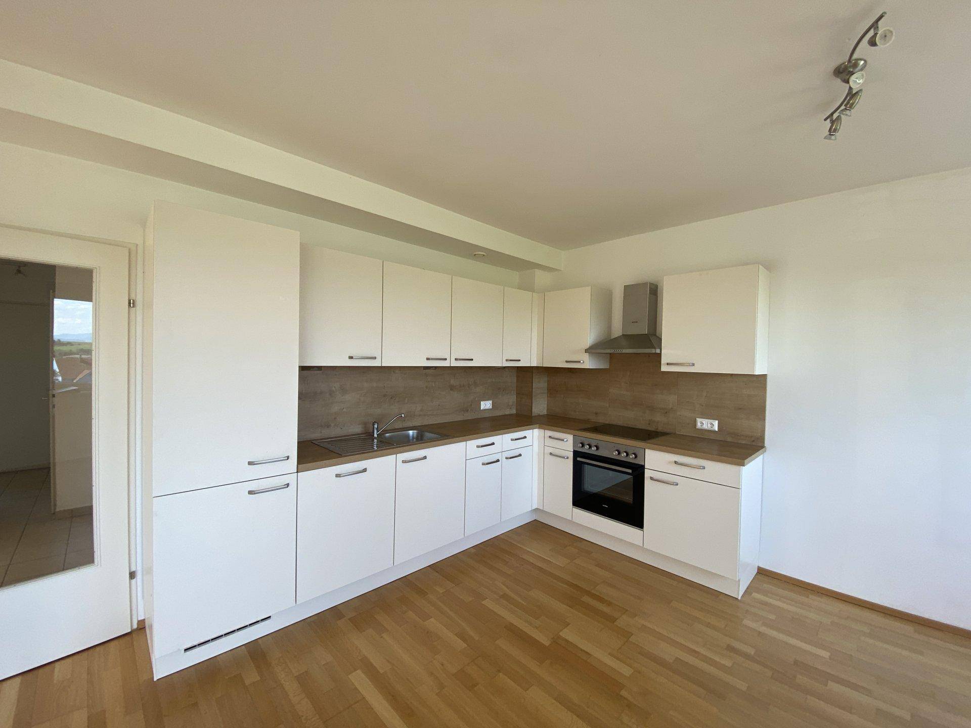 Moderne Einbauküche mit weißen Schränken, Holz-Arbeitsplatten und integrierten Geräten.
