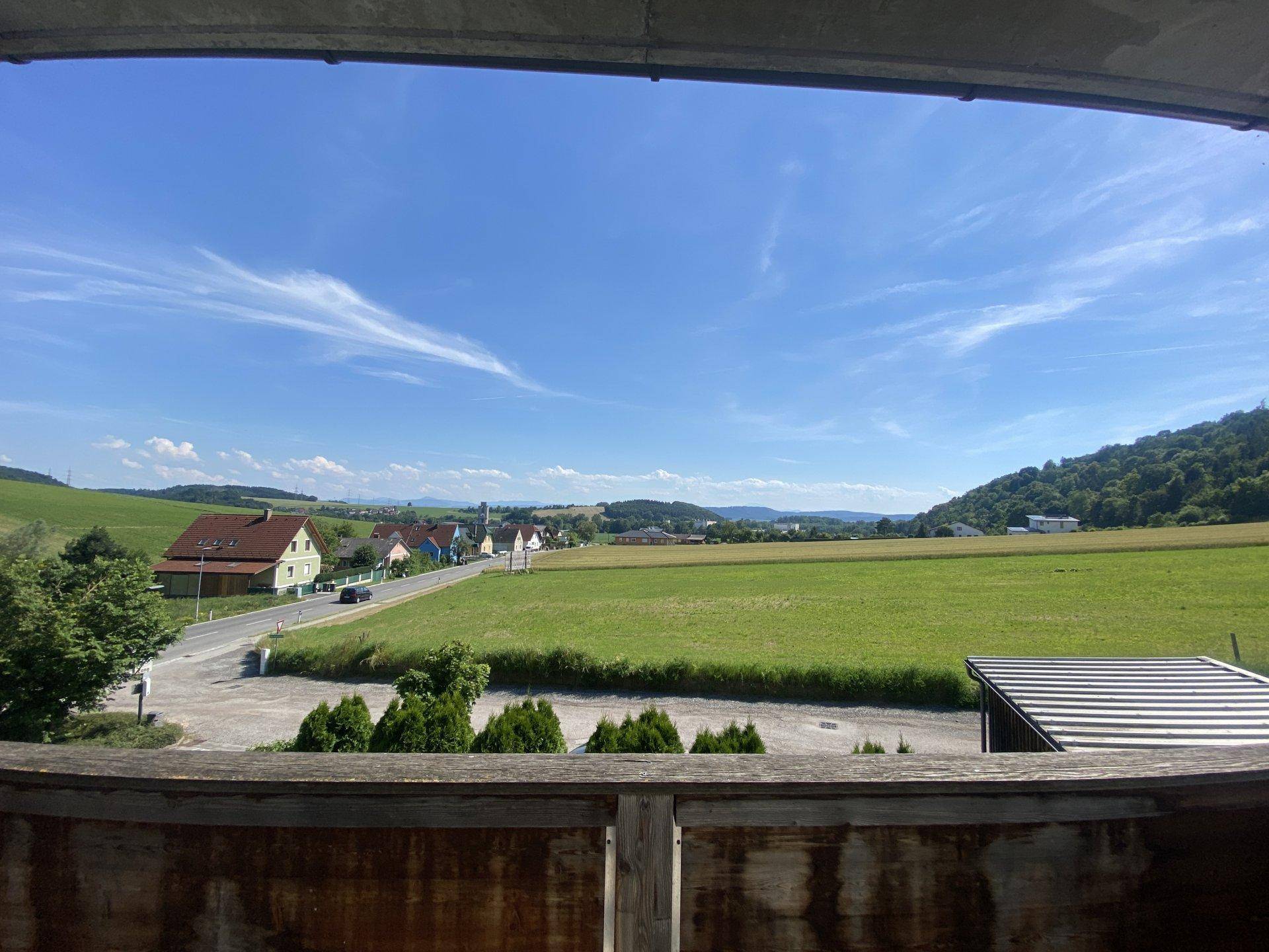 Weitläufiger Blick vom Balkon über grüne Felder und die umliegende Landschaft.
