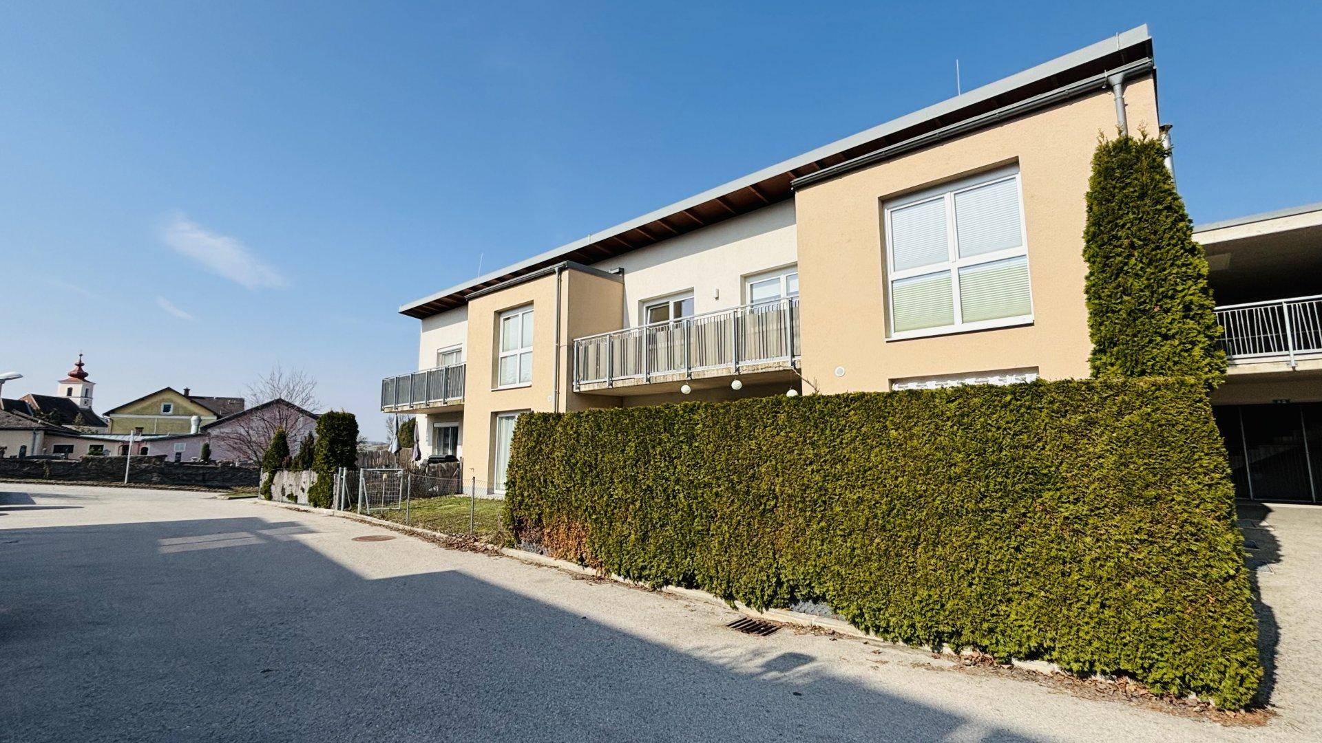 Moderne Wohnanlage mit gepflegter Hecke und Blick auf die umliegende Bebauung.