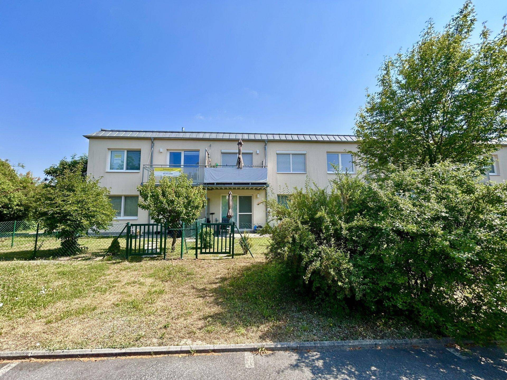 Fassade des Mehrfamilienhauses mit mehreren Balkonen und angrenzender Rasenfläche.