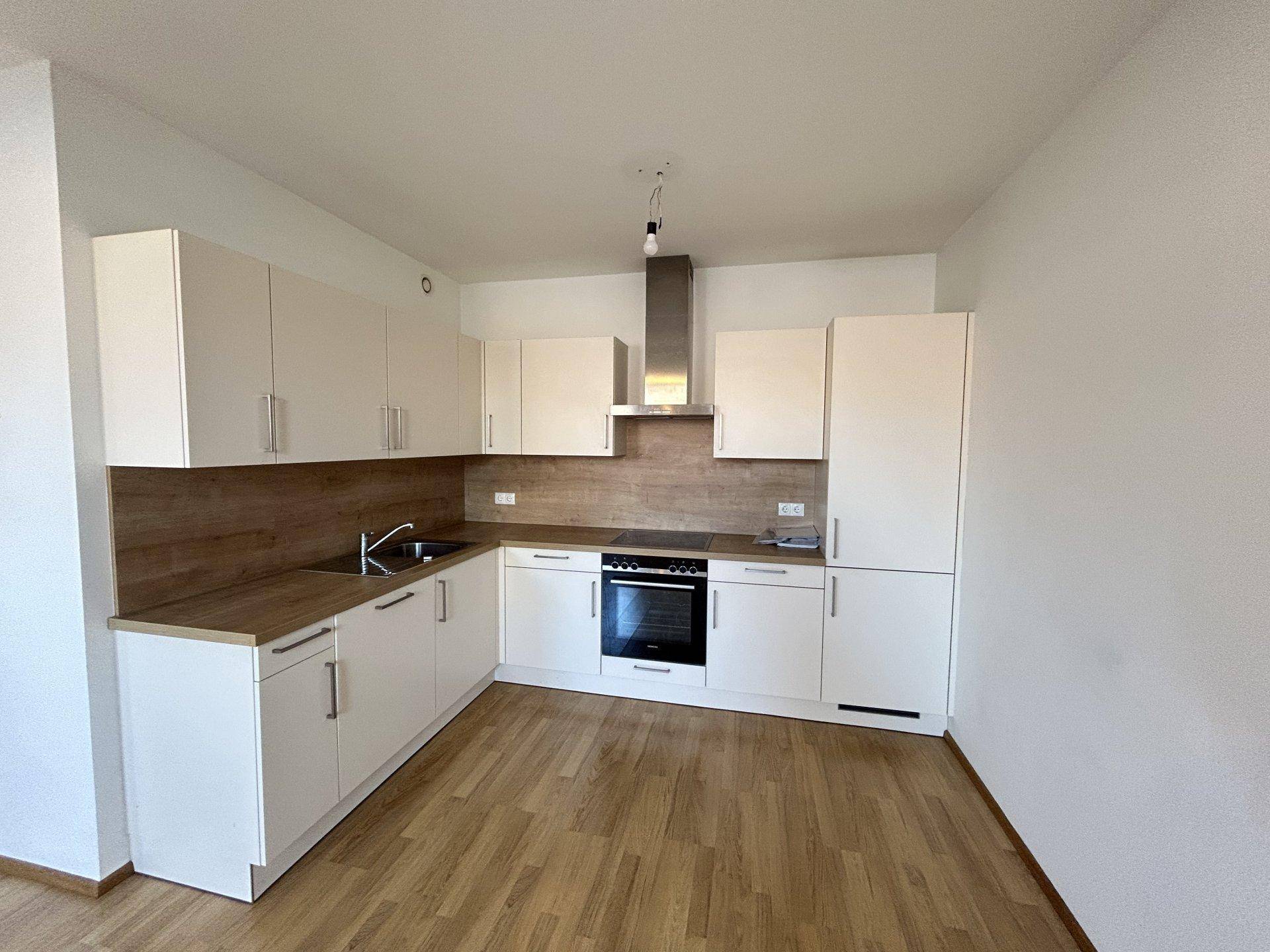 Moderne Einbauküche mit weißen Schränken, Holz-Arbeitsplatte und integrierten Geräten.