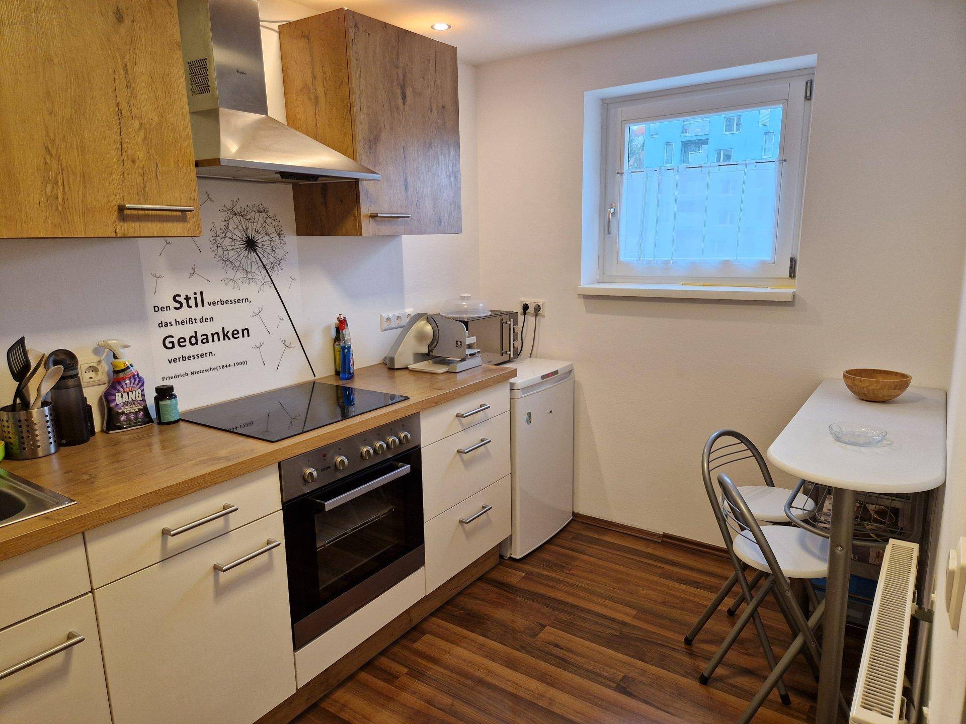 Helle Küche mit Fenster, kleiner Essecke und modernen Einbaugeräten.