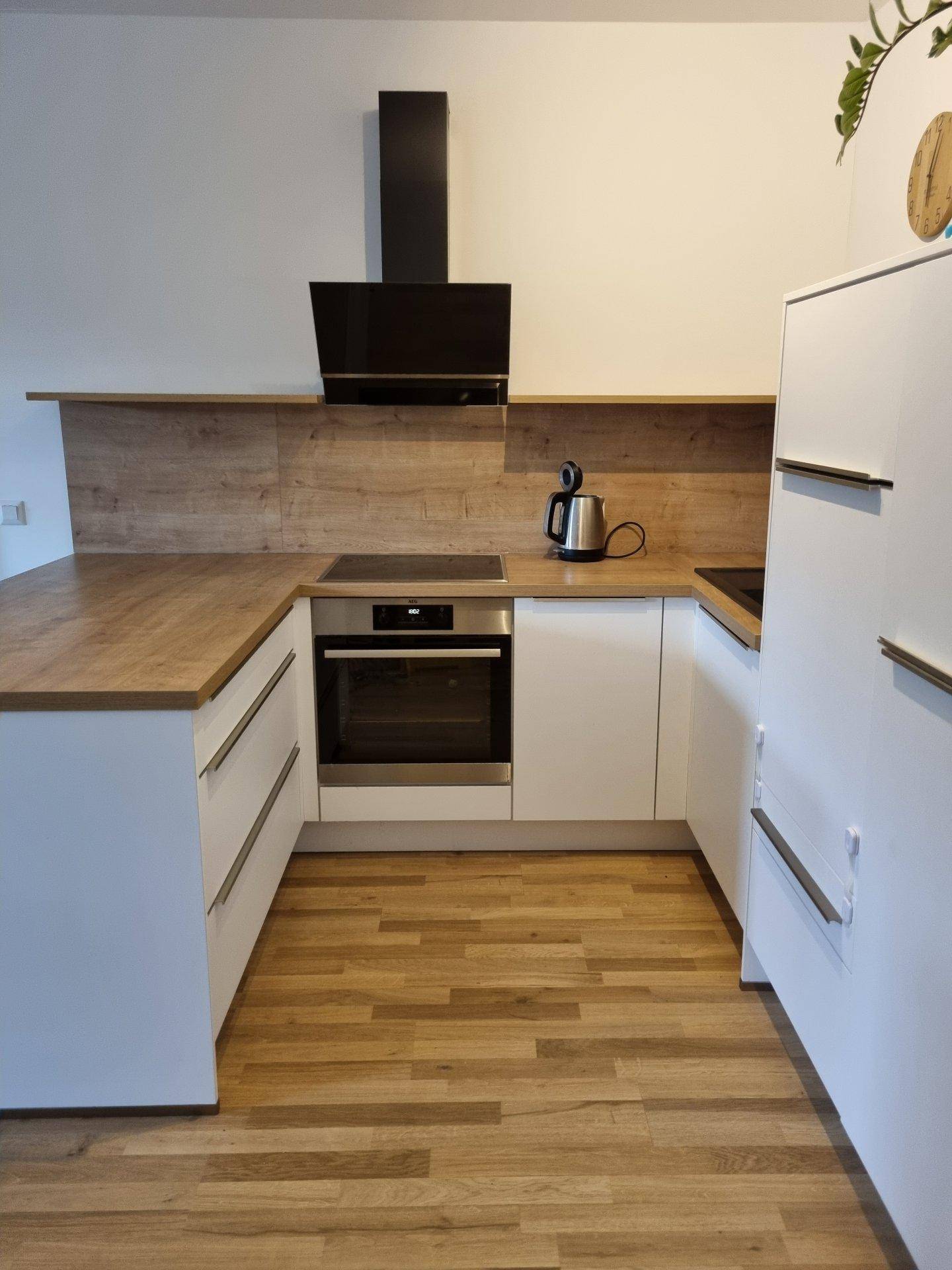 U-förmige Einbauküche mit integriertem Backofen, Holzarbeitsplatten und hellem Holzfußboden.