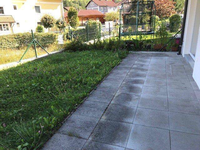 Gepflasterte Terrasse neben einer Rasenfläche mit Blick auf die Nachbarschaft und grüne Umgebung.
