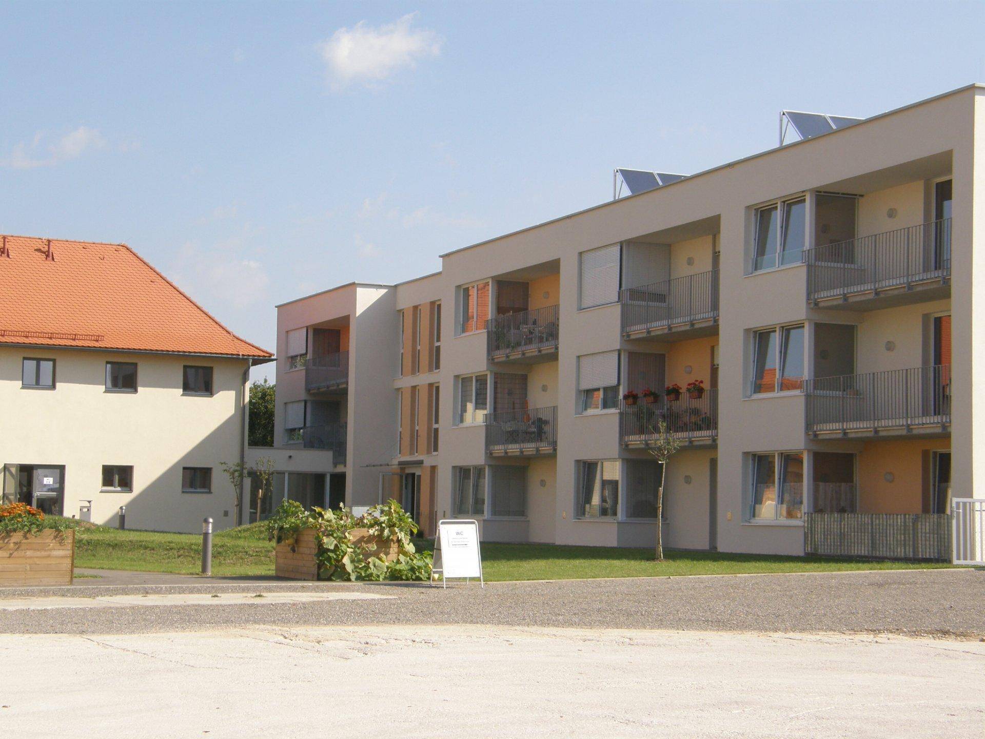 Moderne Wohngebäude mit Balkonen und Solarpaneelen auf dem Dach in einer gepflegten Anlage.