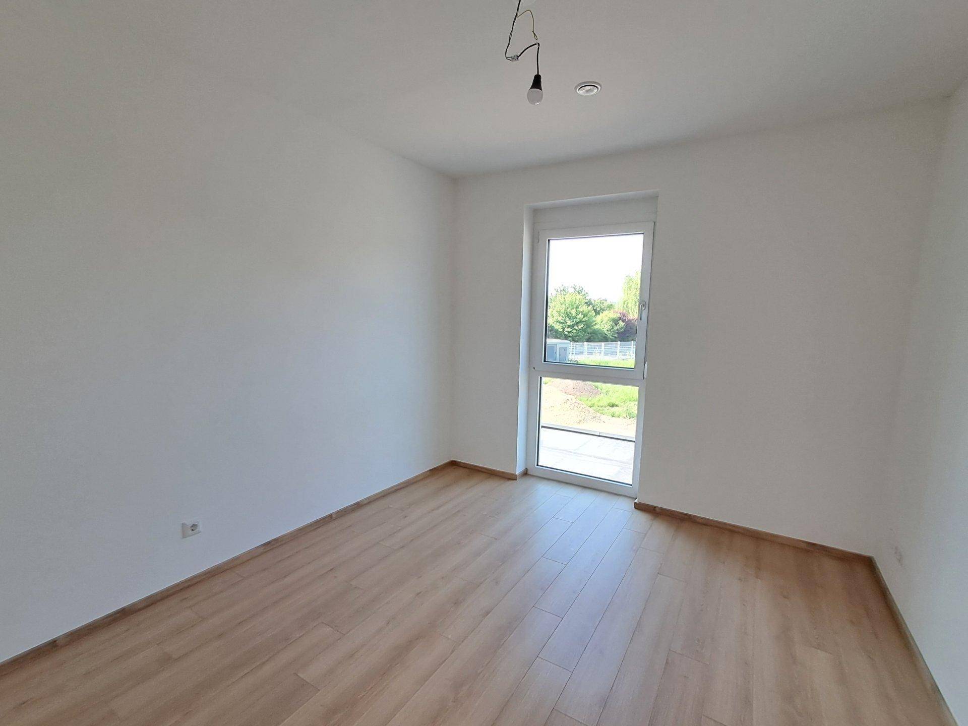 Leeres Zimmer mit Laminatboden und einer Tür zum Balkon oder französischen Balkon.