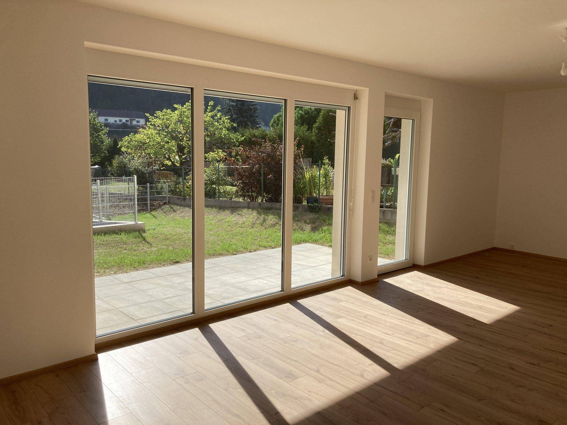 Heller Wohnbereich mit großen Schiebetüren, die den Blick auf den Garten und die Terrasse freigeben.