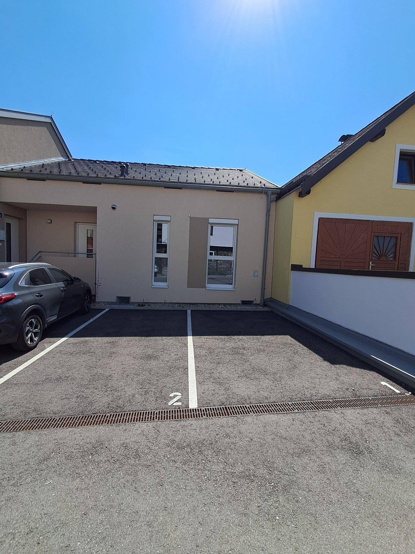 Außenansicht des Hauses mit Parkplatz und klarem blauen Himmel.