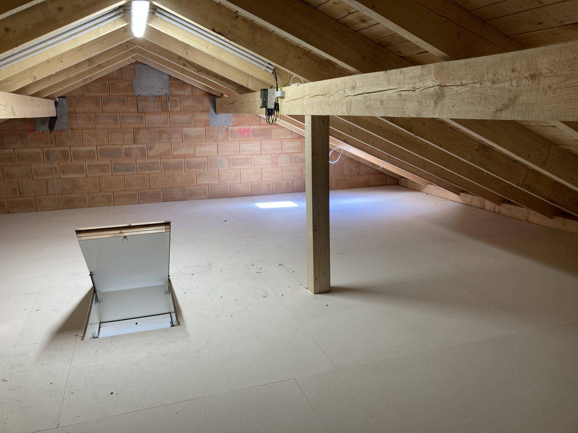 Geräumiger Dachboden mit sichtbaren Holzbalken und Dachfenster, ideal als Stauraum.