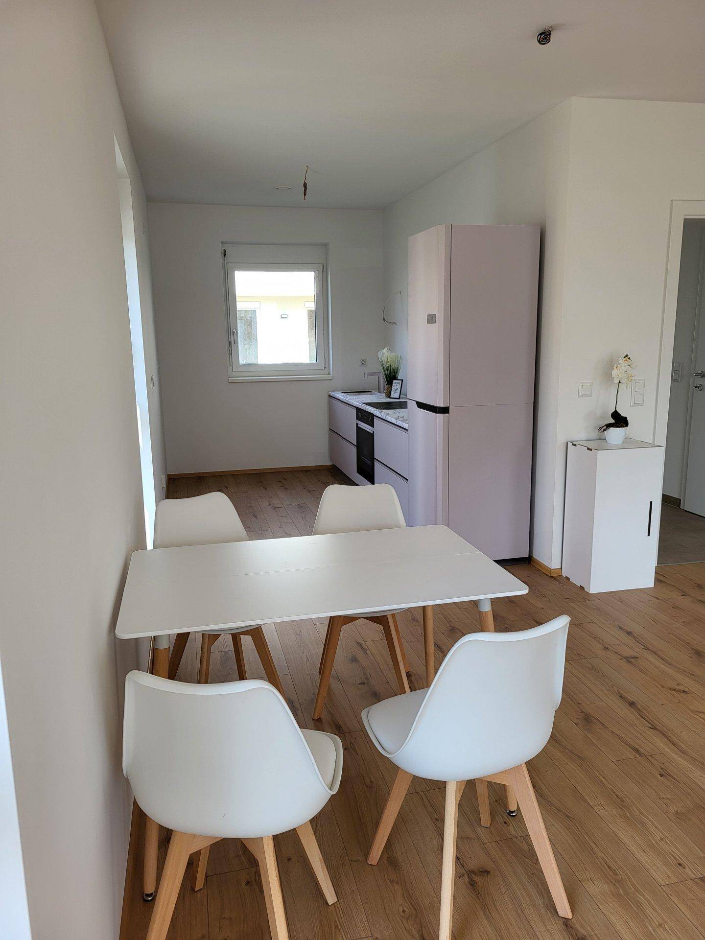 Funktionale Küche mit kleinem Esstisch, Kühlschrank und Fenster, ideal für den täglichen Gebrauch.