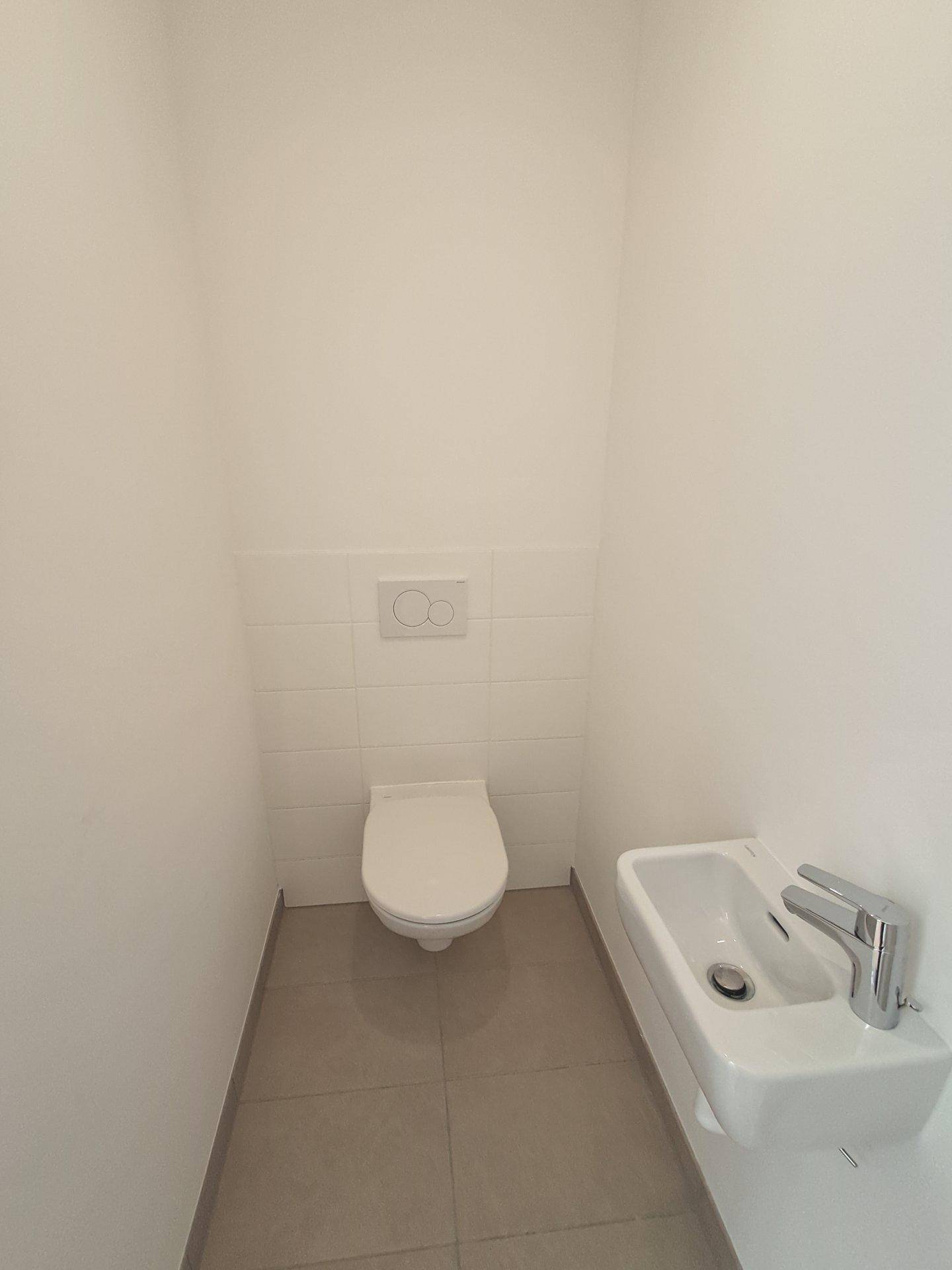 Modernes Gäste-WC mit wandhängendem WC und kleinem Waschbecken, in schlichtem Design.