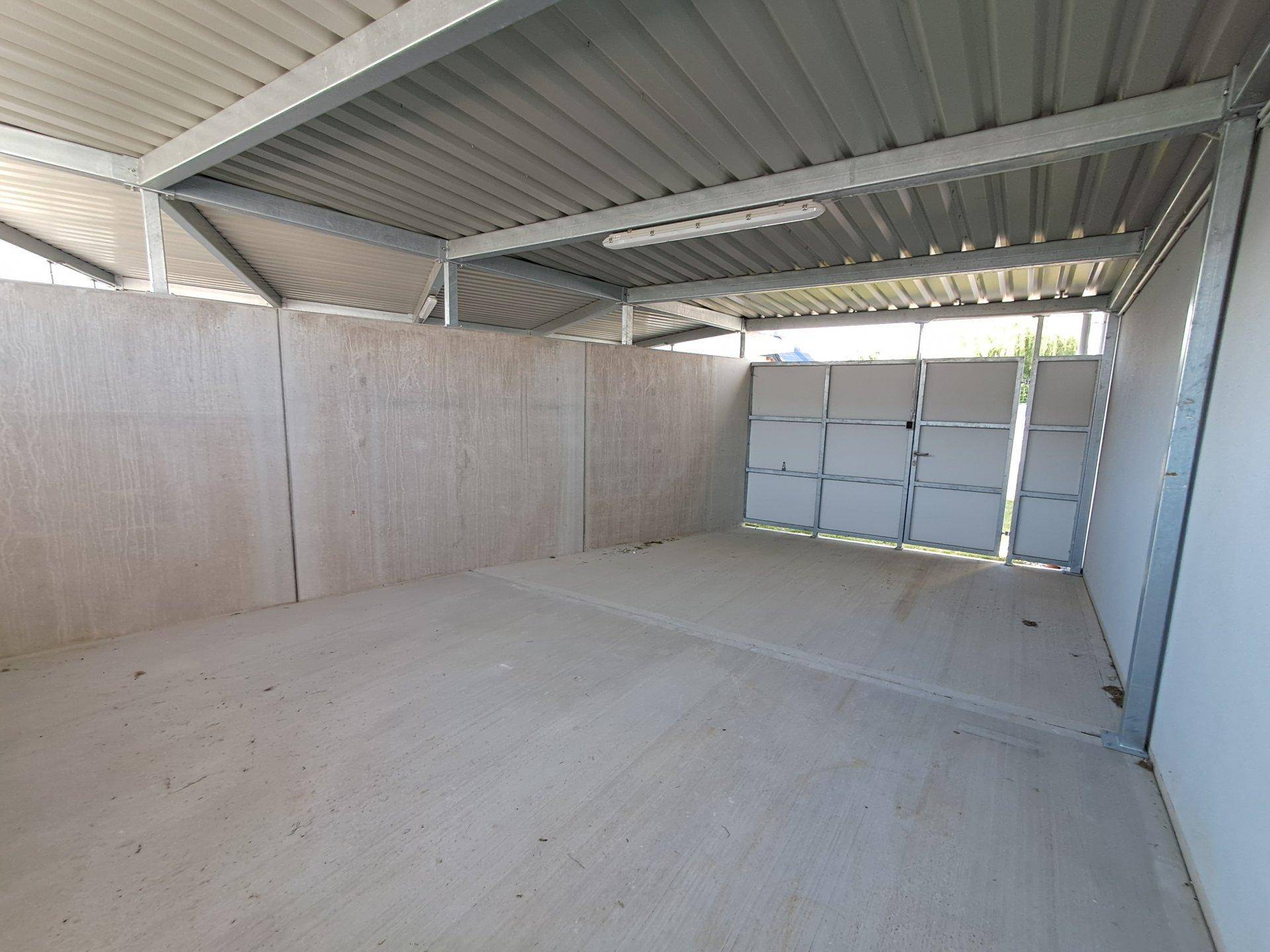 Geräumige Garage oder Carport mit Betonboden, bietet Platz für Fahrzeuge und Lagerung.