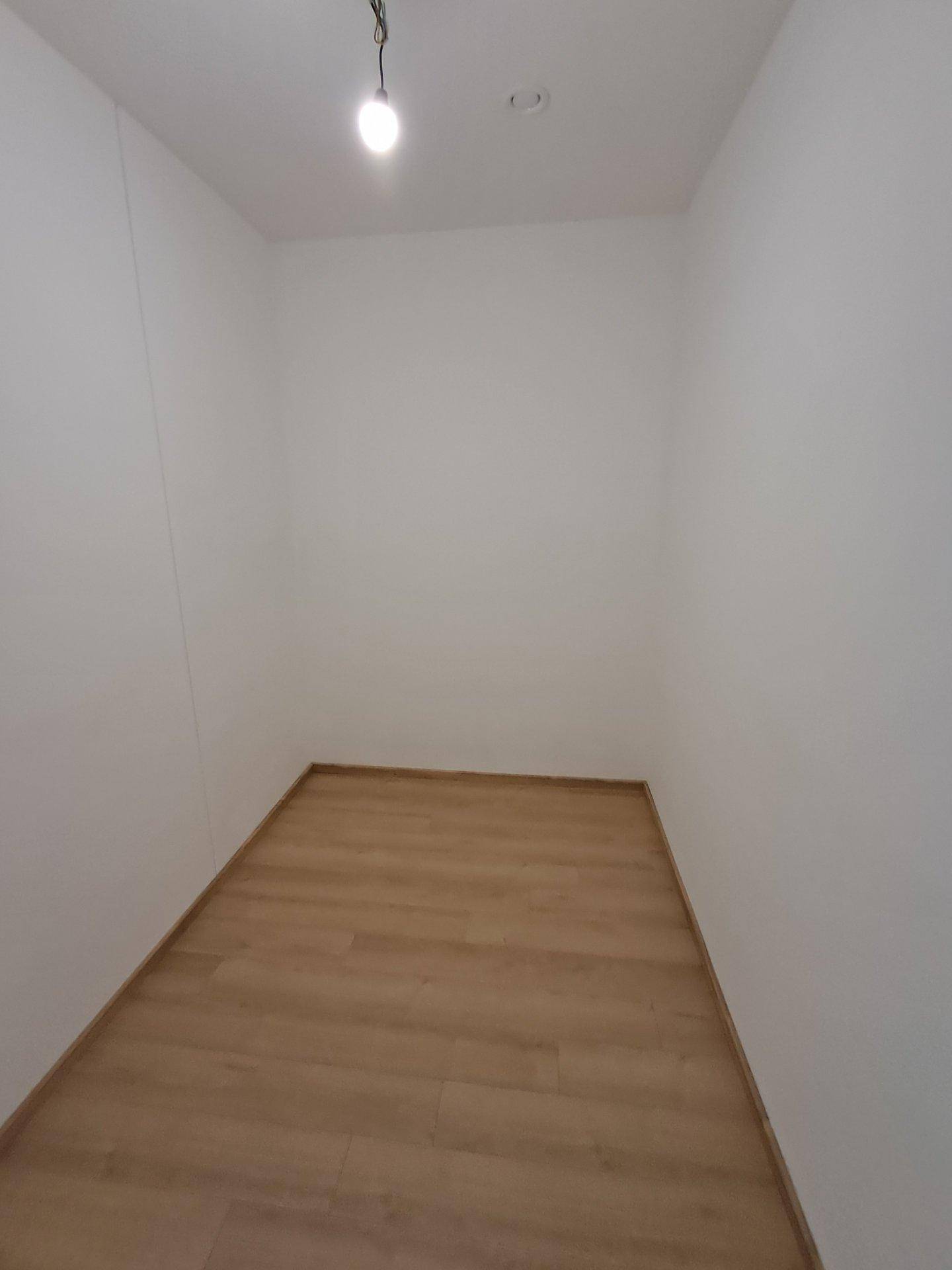 Kleiner, leerer Abstellraum mit hellem Holzboden, ideal für zusätzlichen Stauraum.