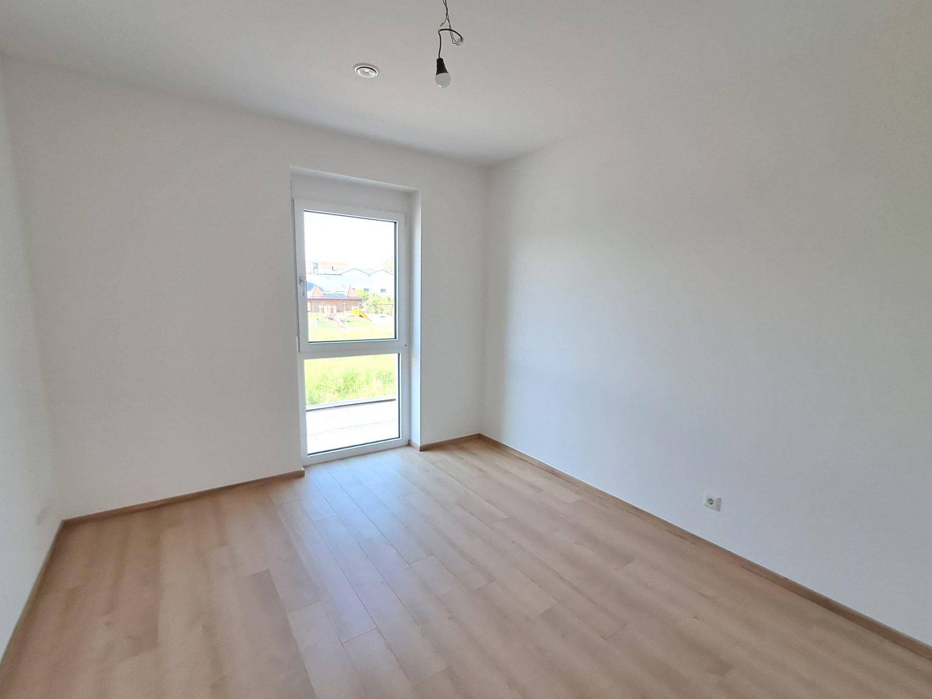 Helles Schlafzimmer mit Holzboden und großem Fenster für viel Tageslicht.