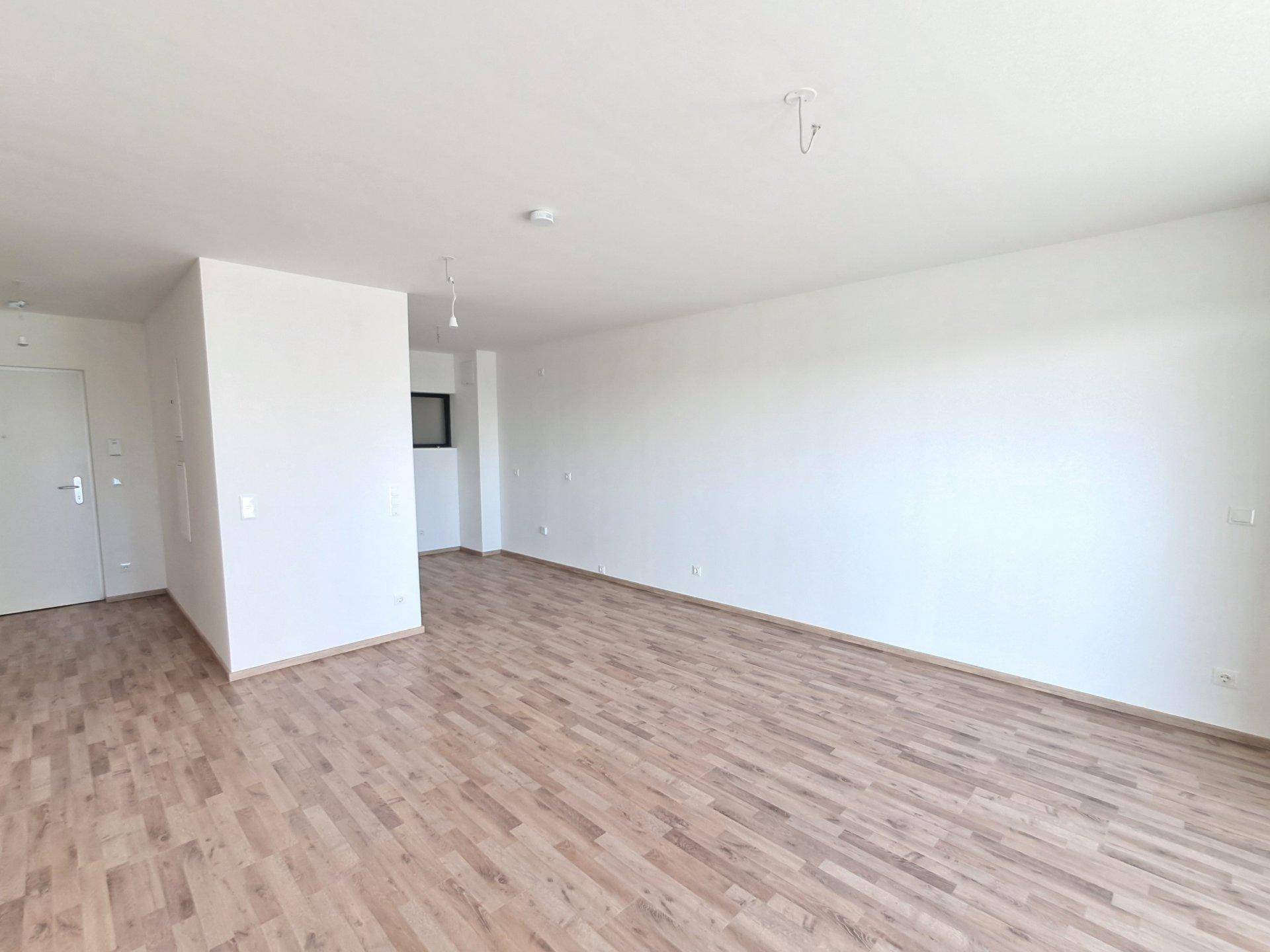 Heller, leerer Raum mit Holzboden und weißen Wänden, bereit zur individuellen Gestaltung.