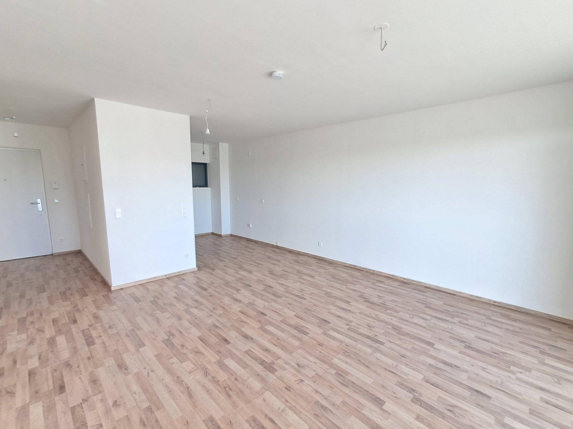 Heller, leerer Wohnbereich mit Holzboden und weißen Wänden, bereit zur individuellen Gestaltung.